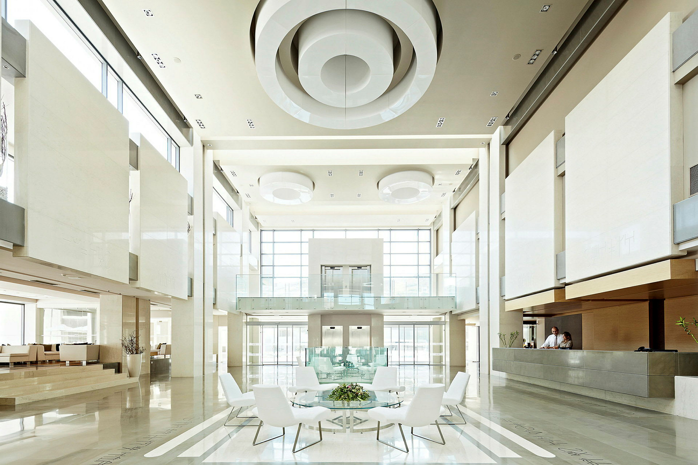 En modern och ljus hotellobby med stora fönster, högt i tak, sittplatser och receptionsdisk. (AI-genererad text)