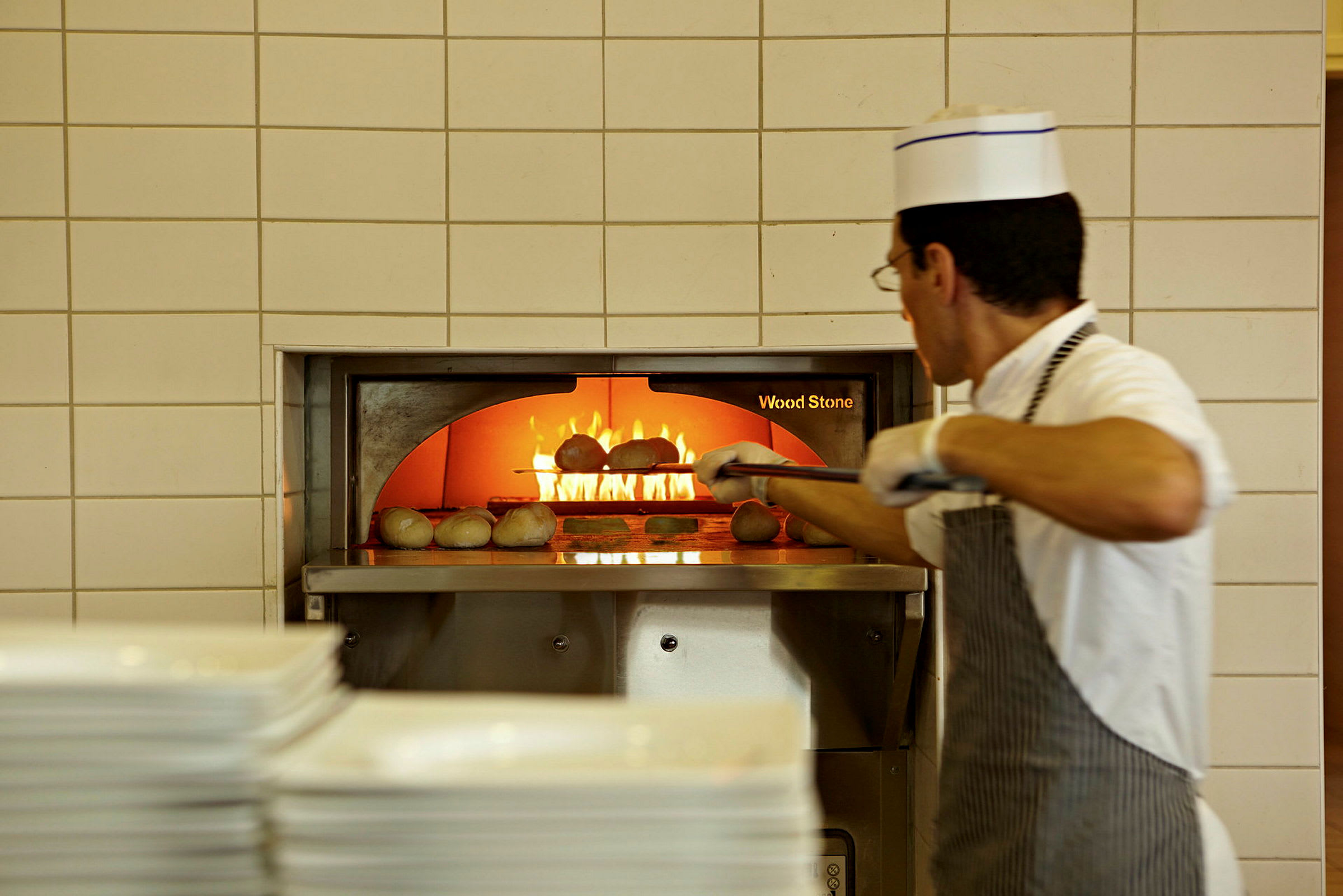 Kock som bakar bröd i en vedugn. (AI-genererad text)