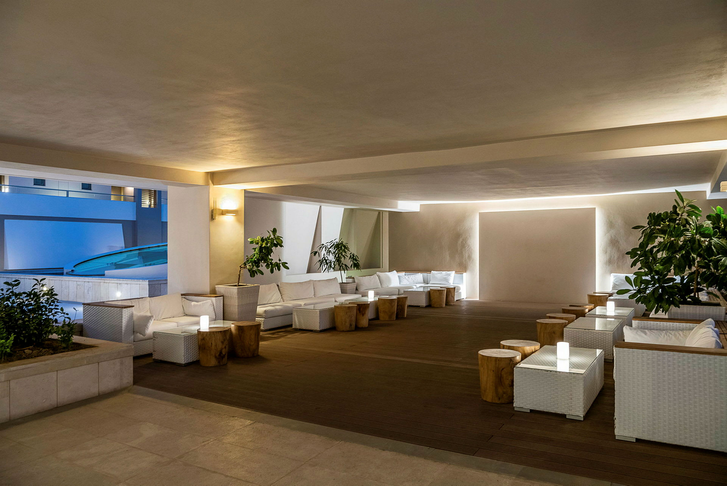 En modern och elegant lounge med vita möbler och träbord, omgivna av växter. (AI-genererad text)