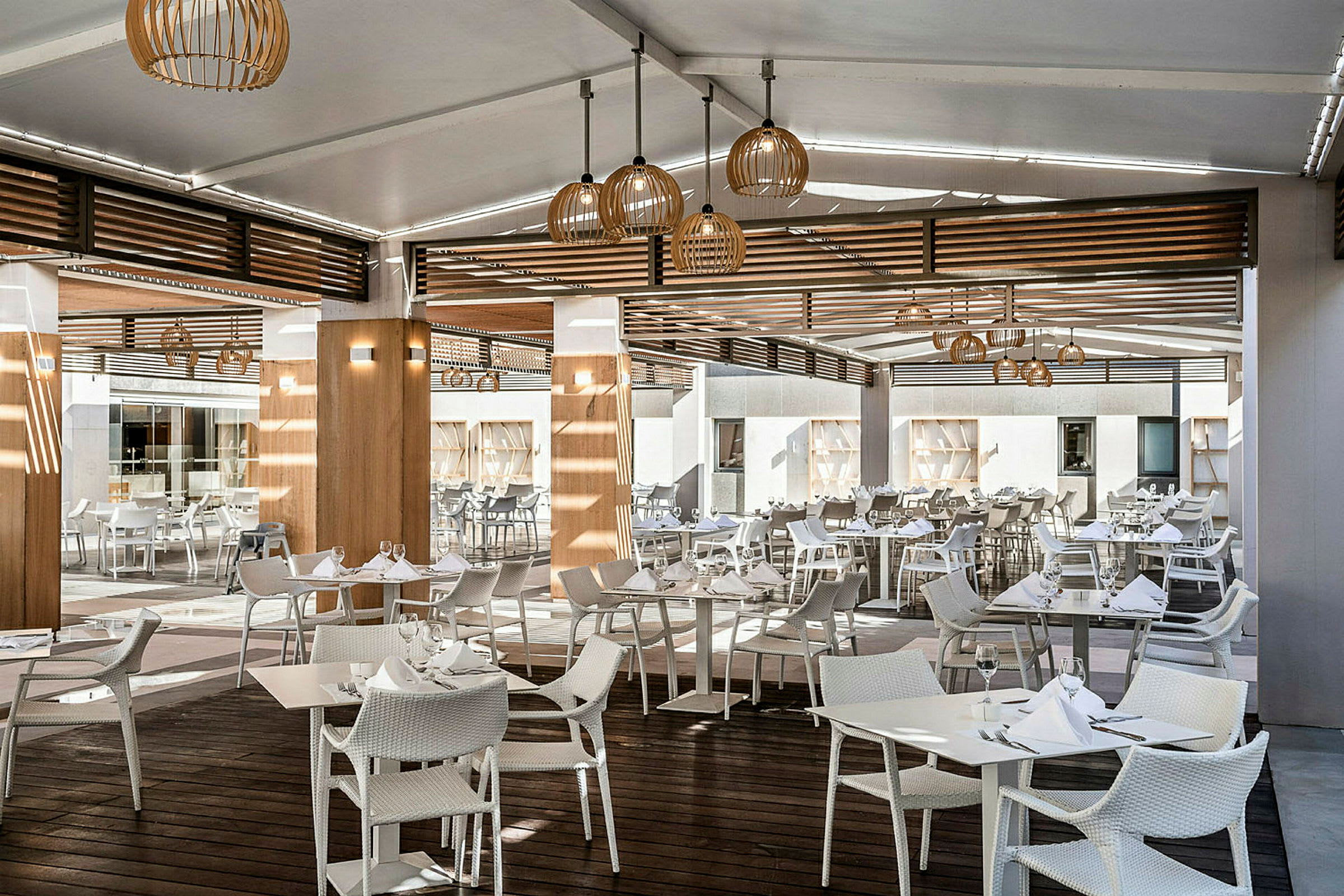 Restaurang med moderna vita bord och stolar under en täckt utomhusmiljö. (AI-genererad text)