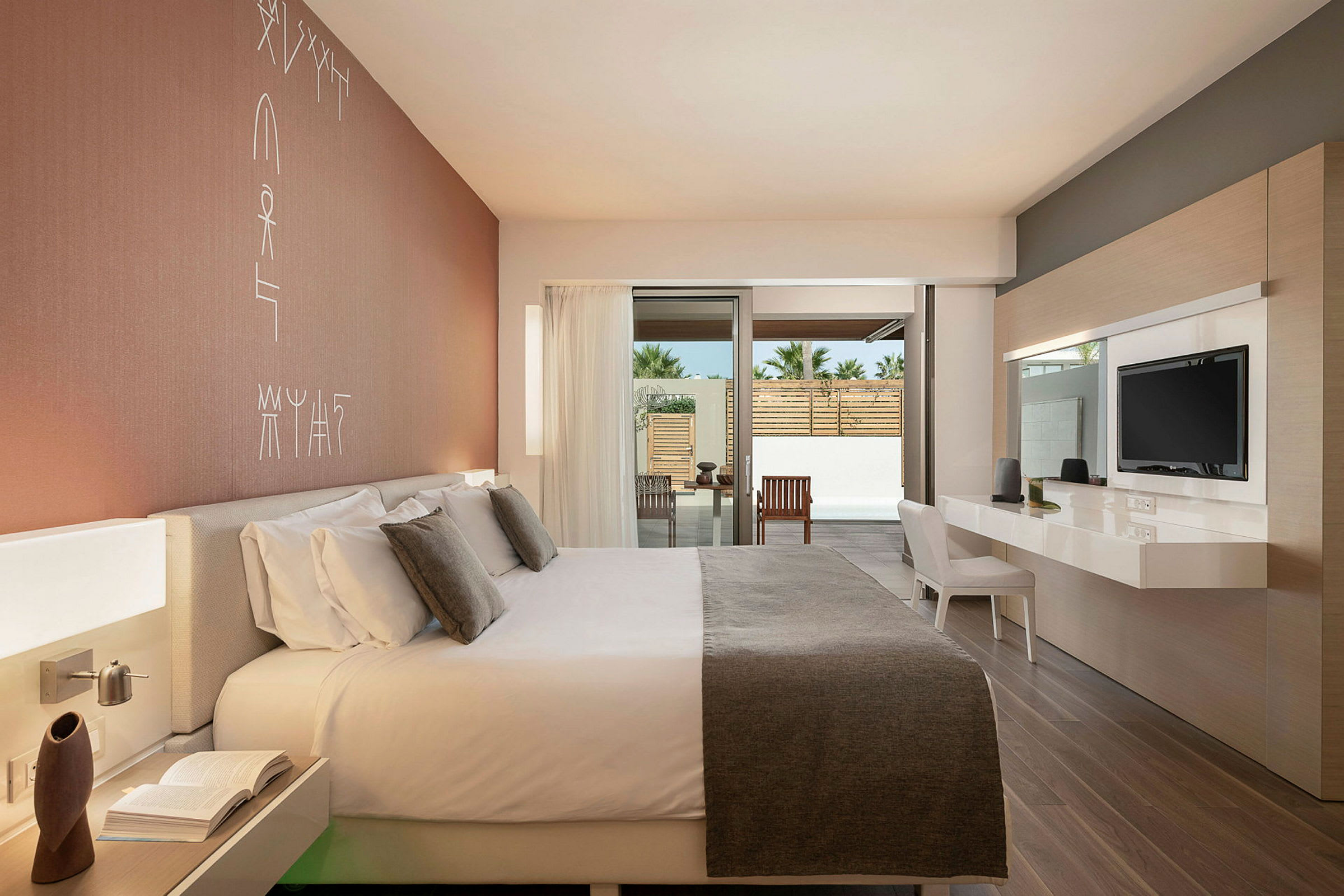 Modernt hotellrum med stor säng och skrivbord, öppet fönster mot en terrass. (AI-genererad text)