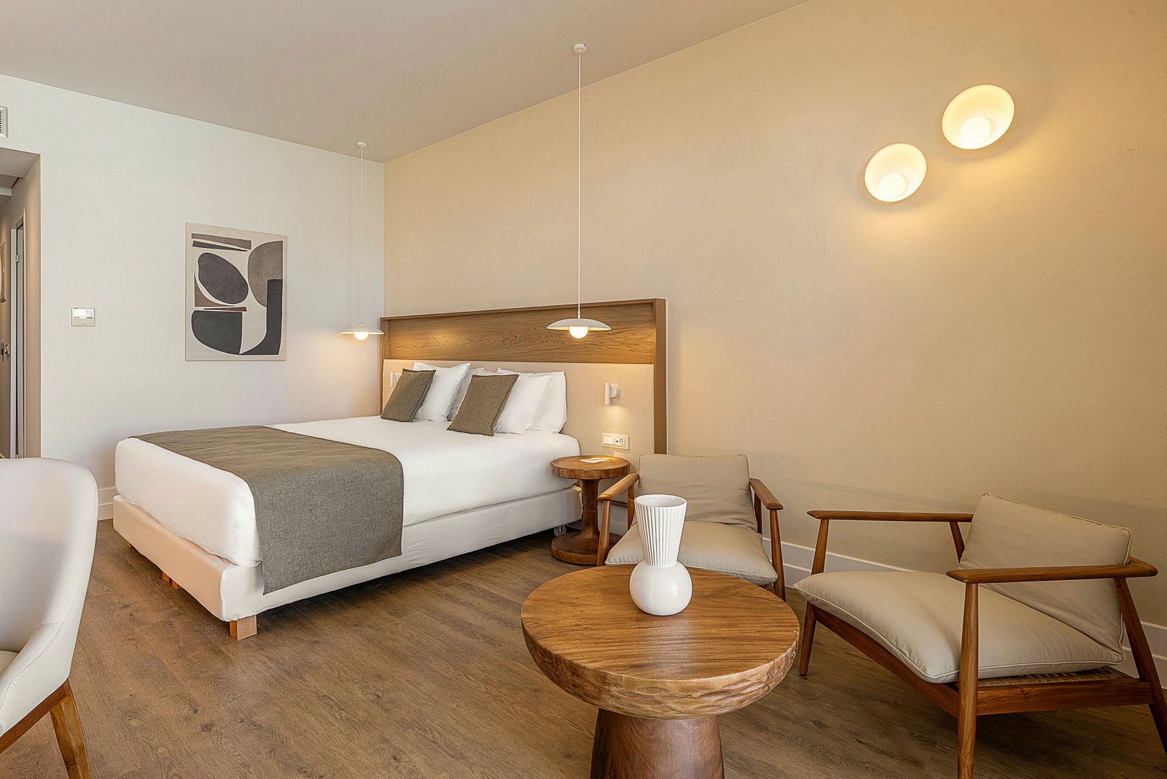 Ett hotellrum med en dubbelsäng, trämöbler och modern belysning. (AI-genererad text)