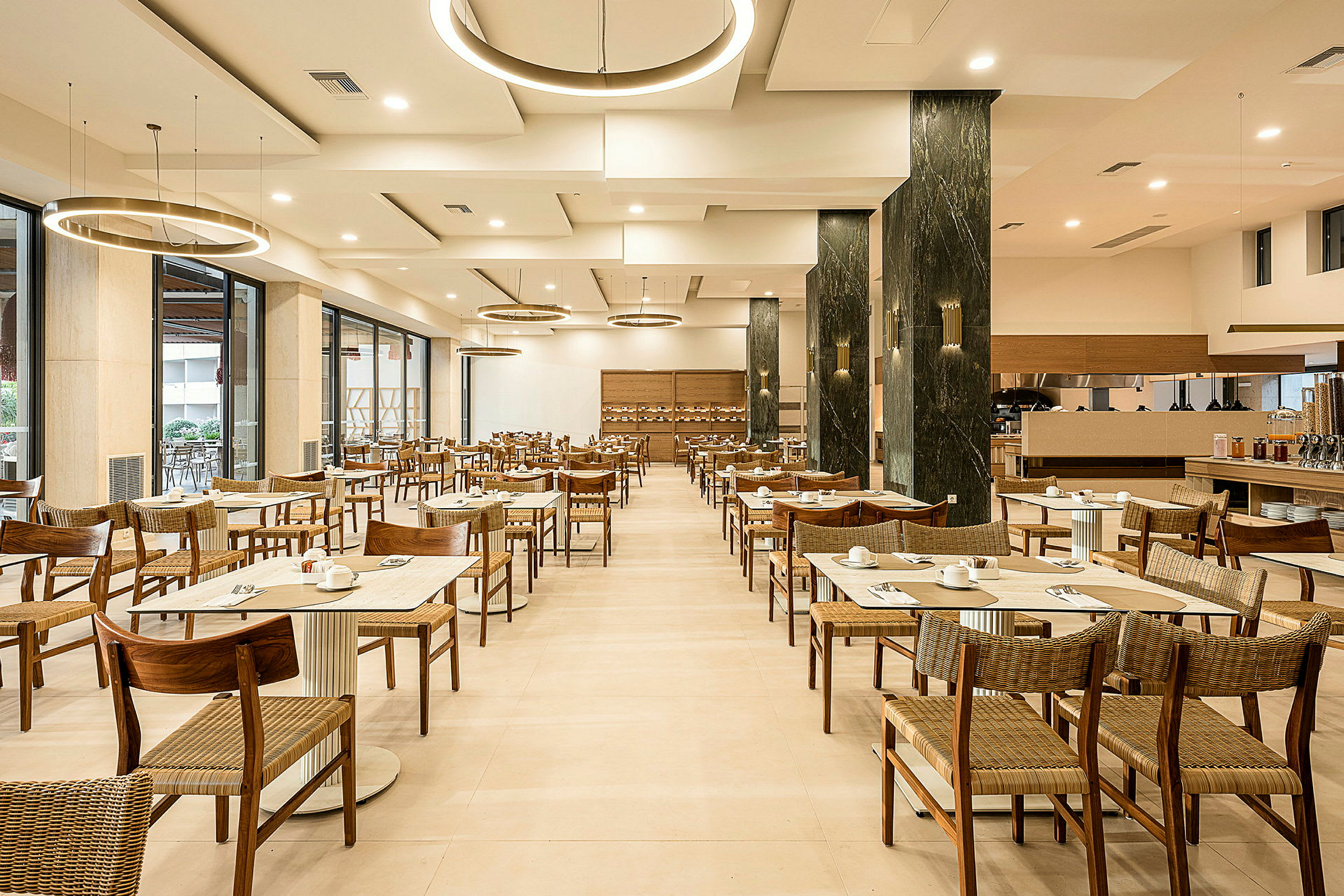 En restaurang med dukade bord och stolar, moderna lampor i taket och ljus inredning. (AI-genererad text)