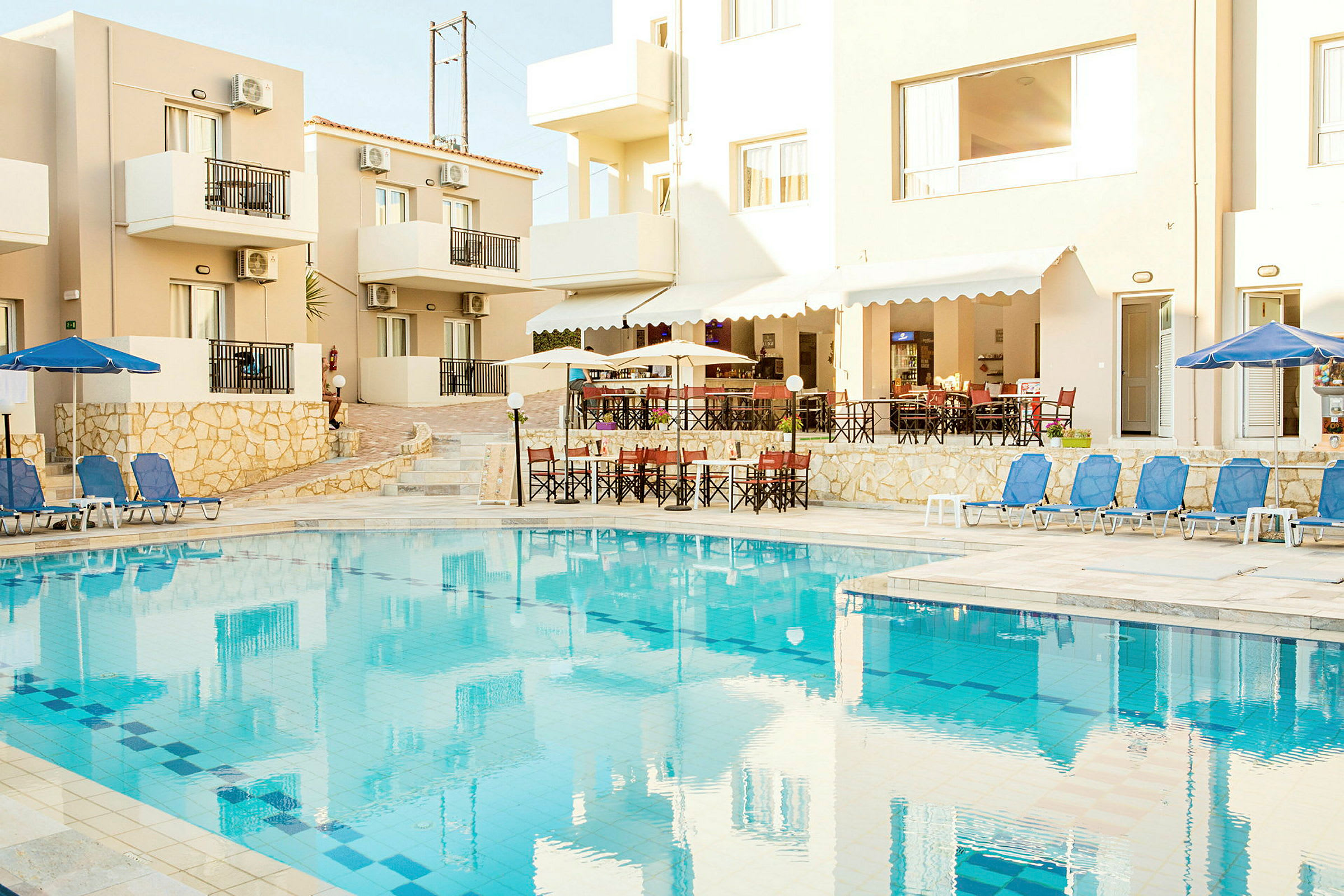 Bild av en hotellbyggnad med balkonger och en pool med solstolar. (AI-genererad text)