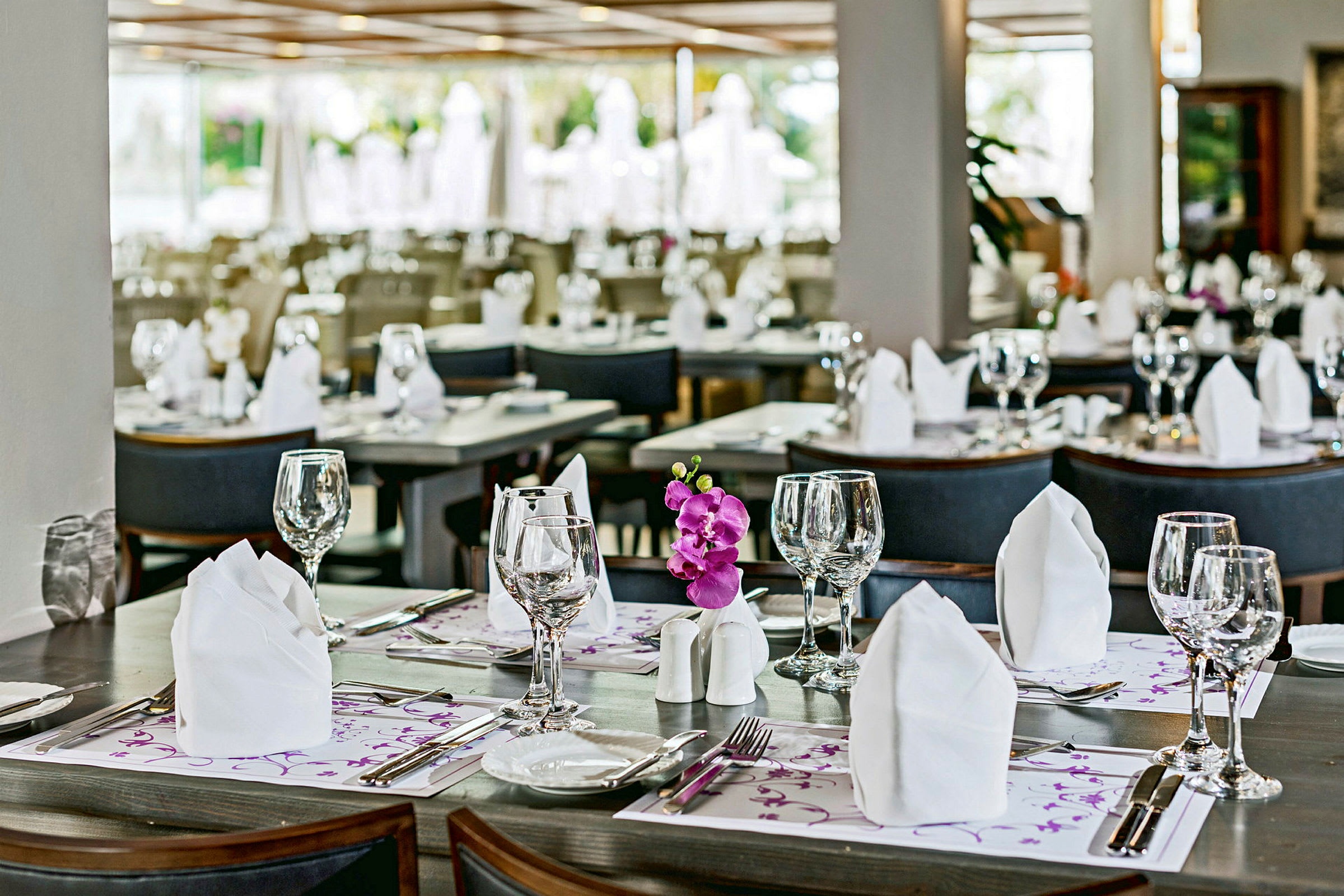 En restaurang med dukade bord, inklusive servetter, glas och bestick. (AI-genererad text)