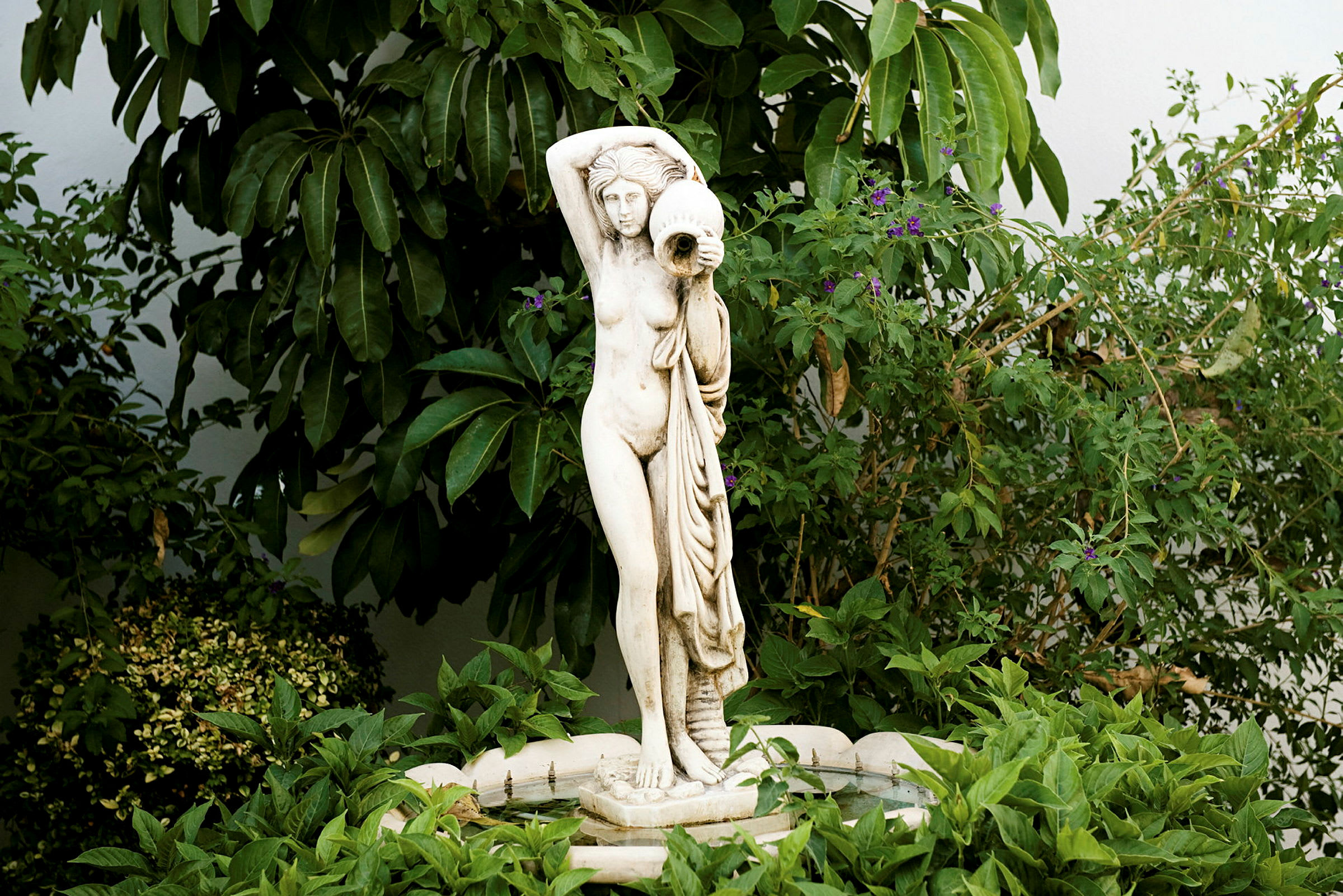 Staty av en stående person omgiven av grönska. (AI-genererad text)