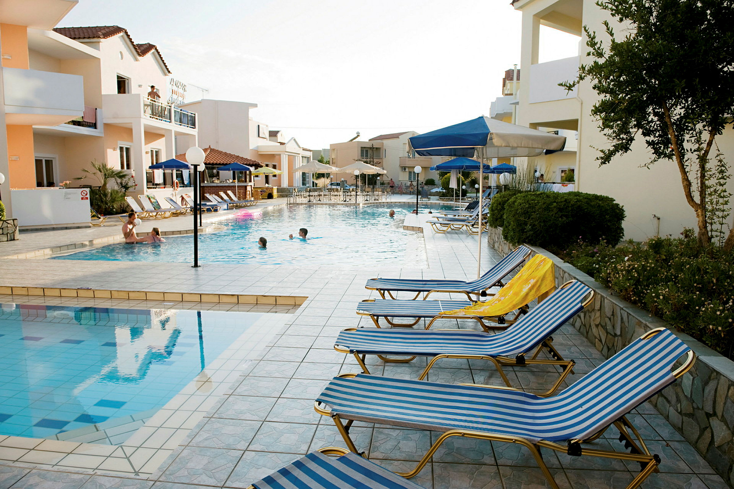 En hotellpool med solstolar och paraplyer runt omkring. (AI-genererad text)