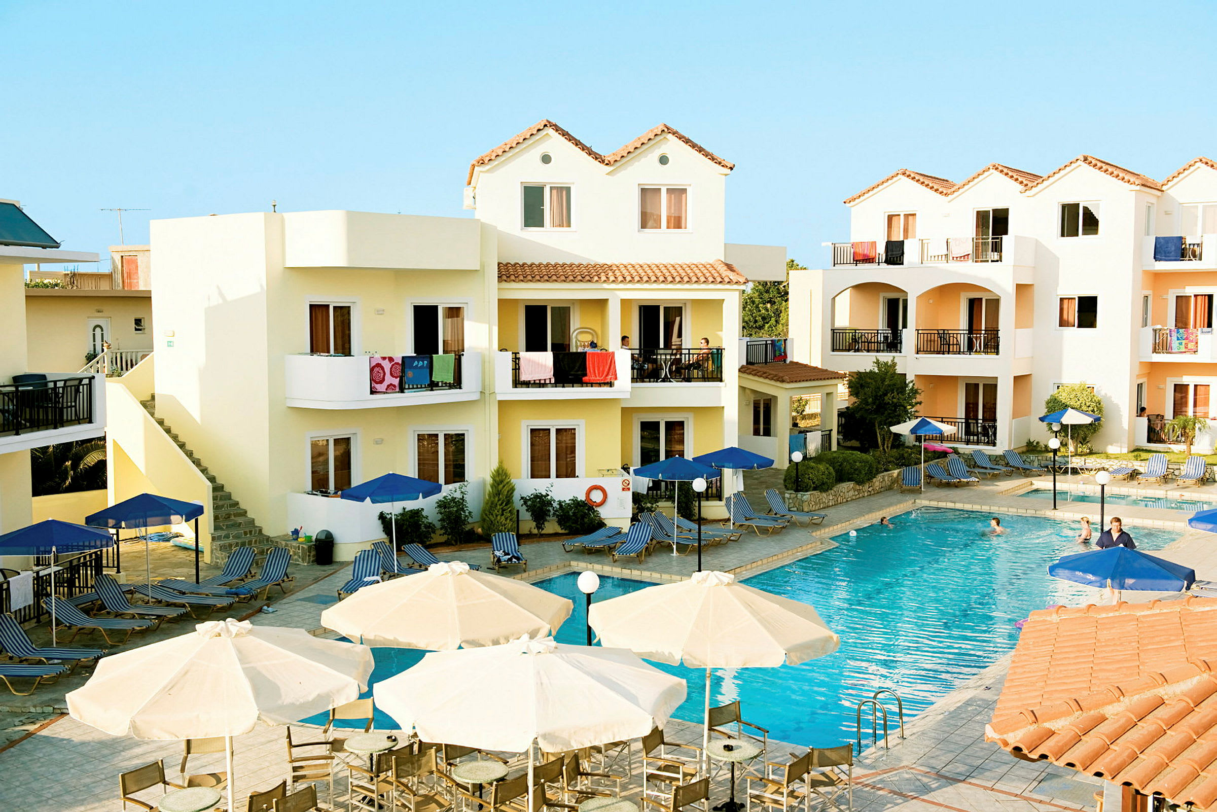 Ett hotellområde med en pool och omgivande byggnader med balkonger. (AI-genererad text)