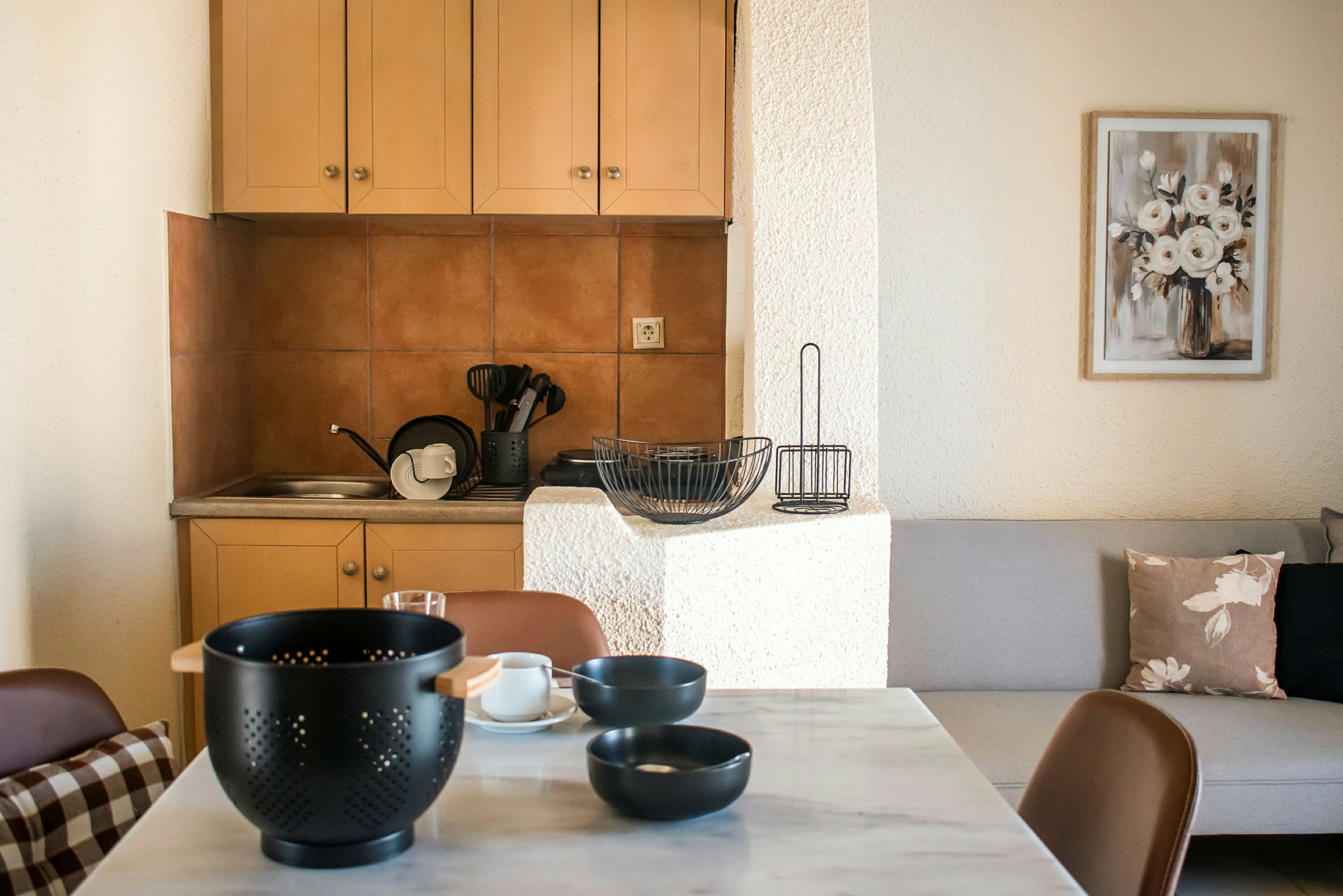 Ett kök med ett matbord i förgrunden, en diskho, köksredskap och ett skåp i bakgrunden. (AI-genererad text)