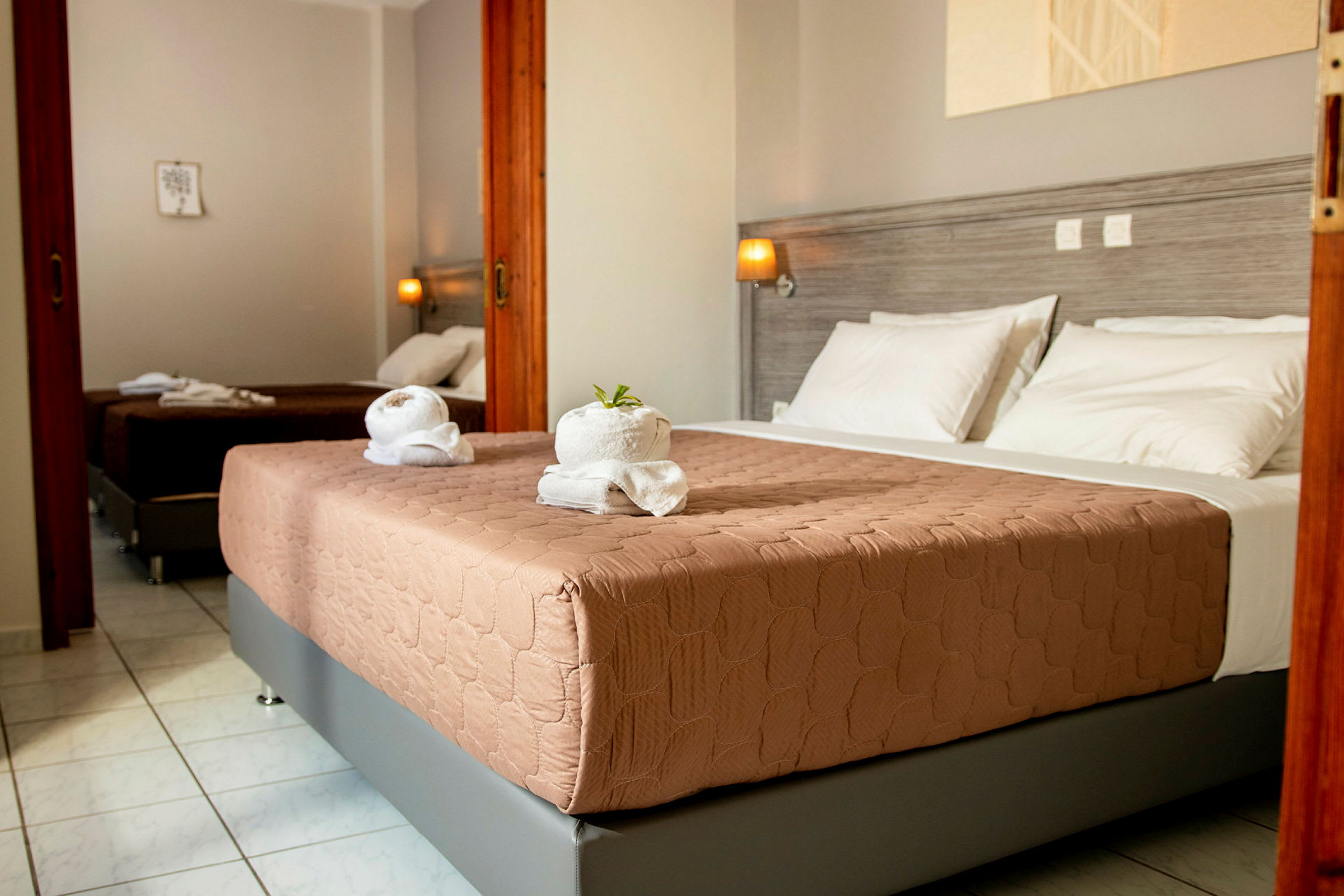 Hotellrum med två sängar, ljusgrå väggar och vit sängkläder. (AI-genererad text)