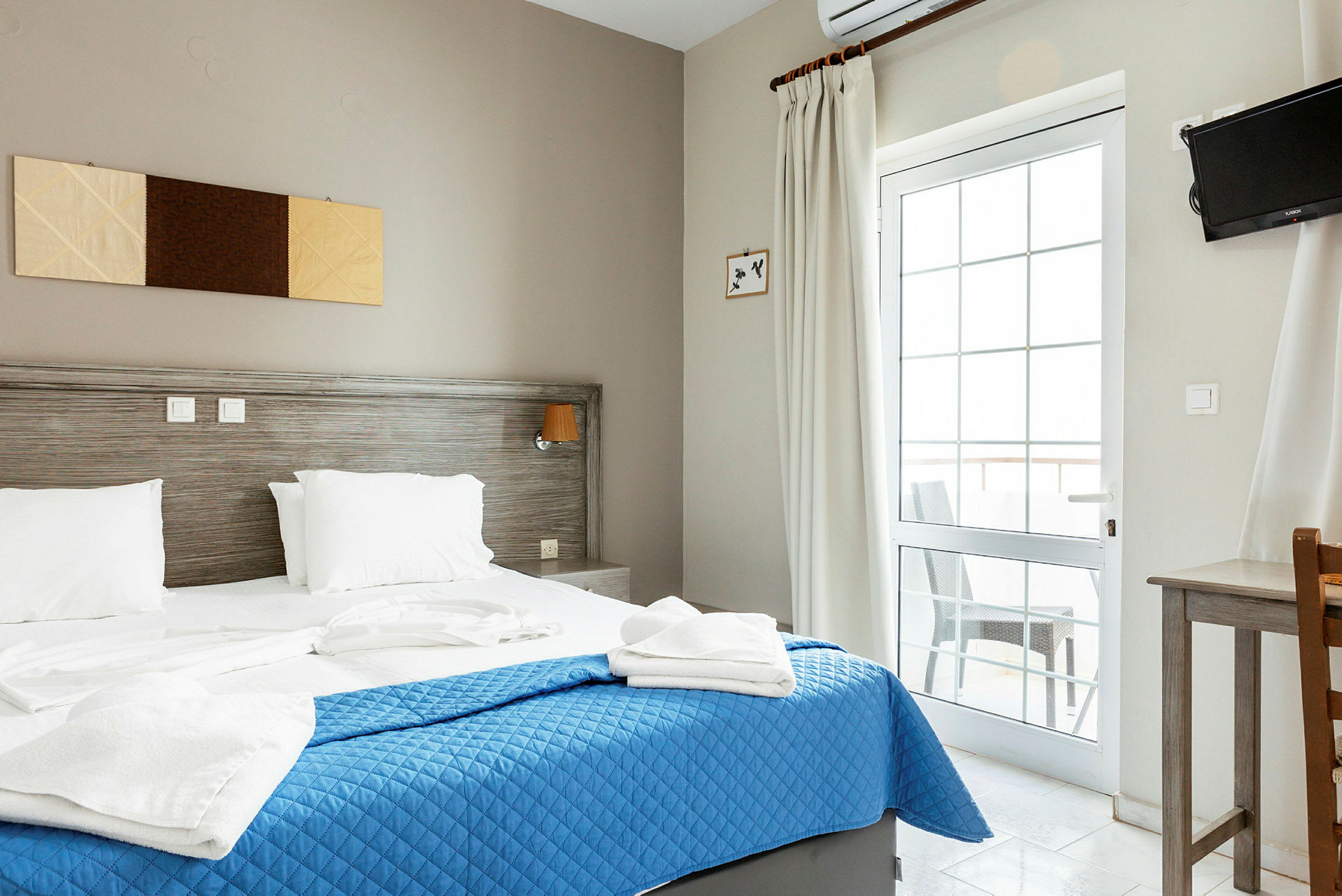 Ett hotellrum med en dubbelsäng, blå överkast och vita sängkläder. (AI-genererad text)