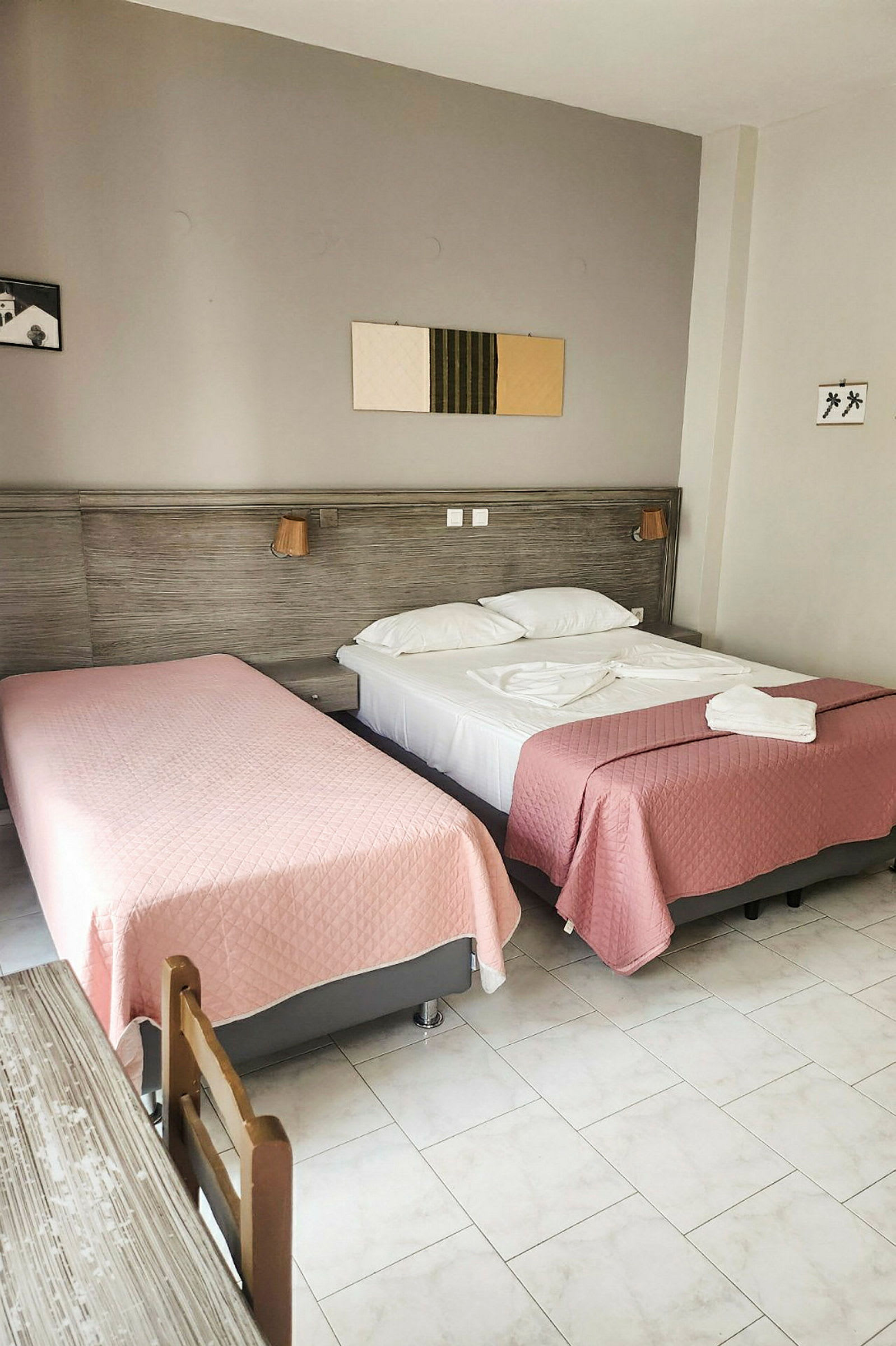 Ett hotellrum med två sängar bäddade med rosa överkast. (AI-genererad text)