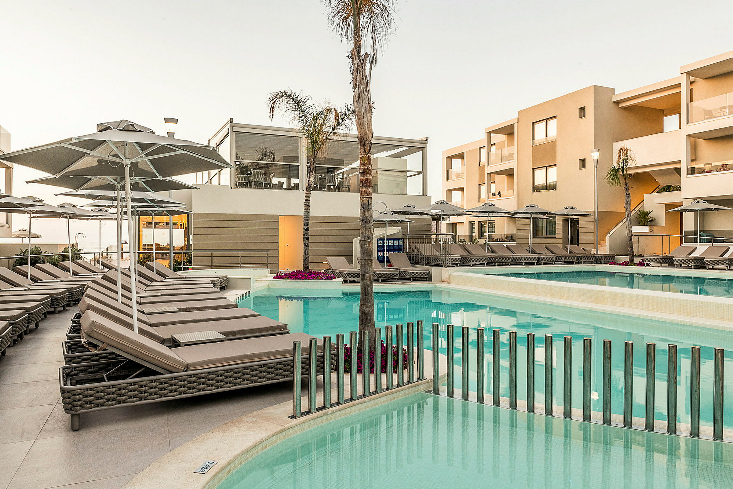 Hotellets poolområde med solstolar och parasoller. (AI-genererad text)