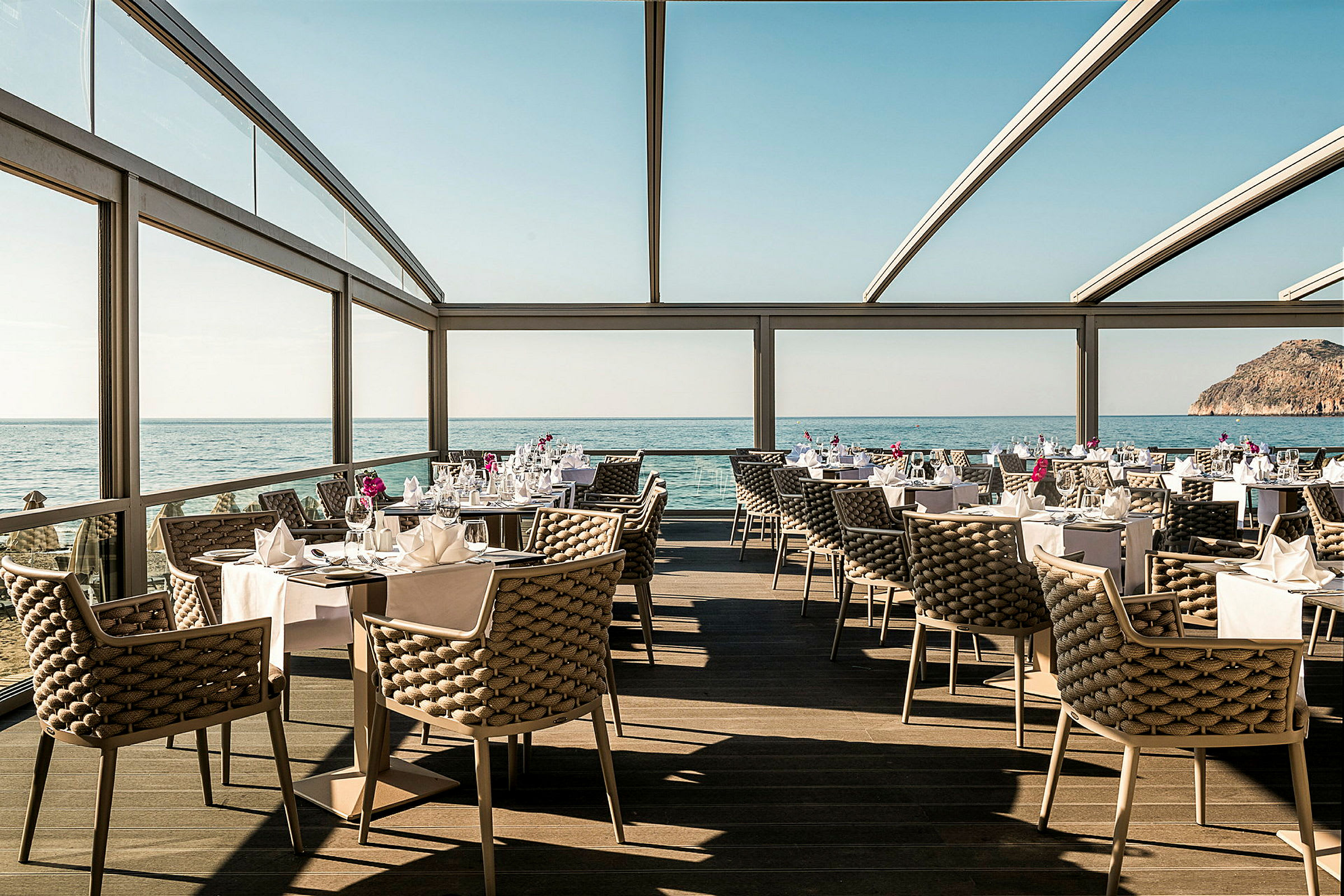 Restaurang med havsutsikt, eleganta möbler och dukade bord. (AI-genererad text)