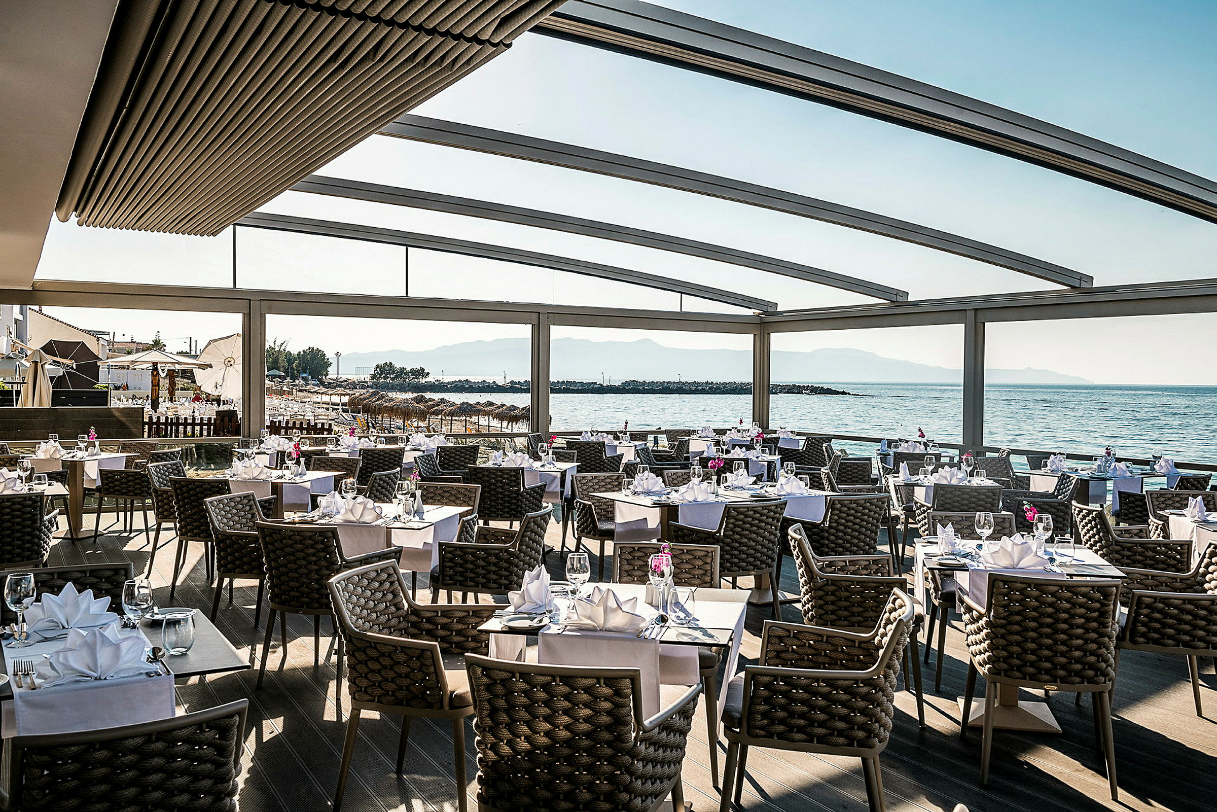 En restaurang med dukade bord och utsikt över havet. (AI-genererad text)