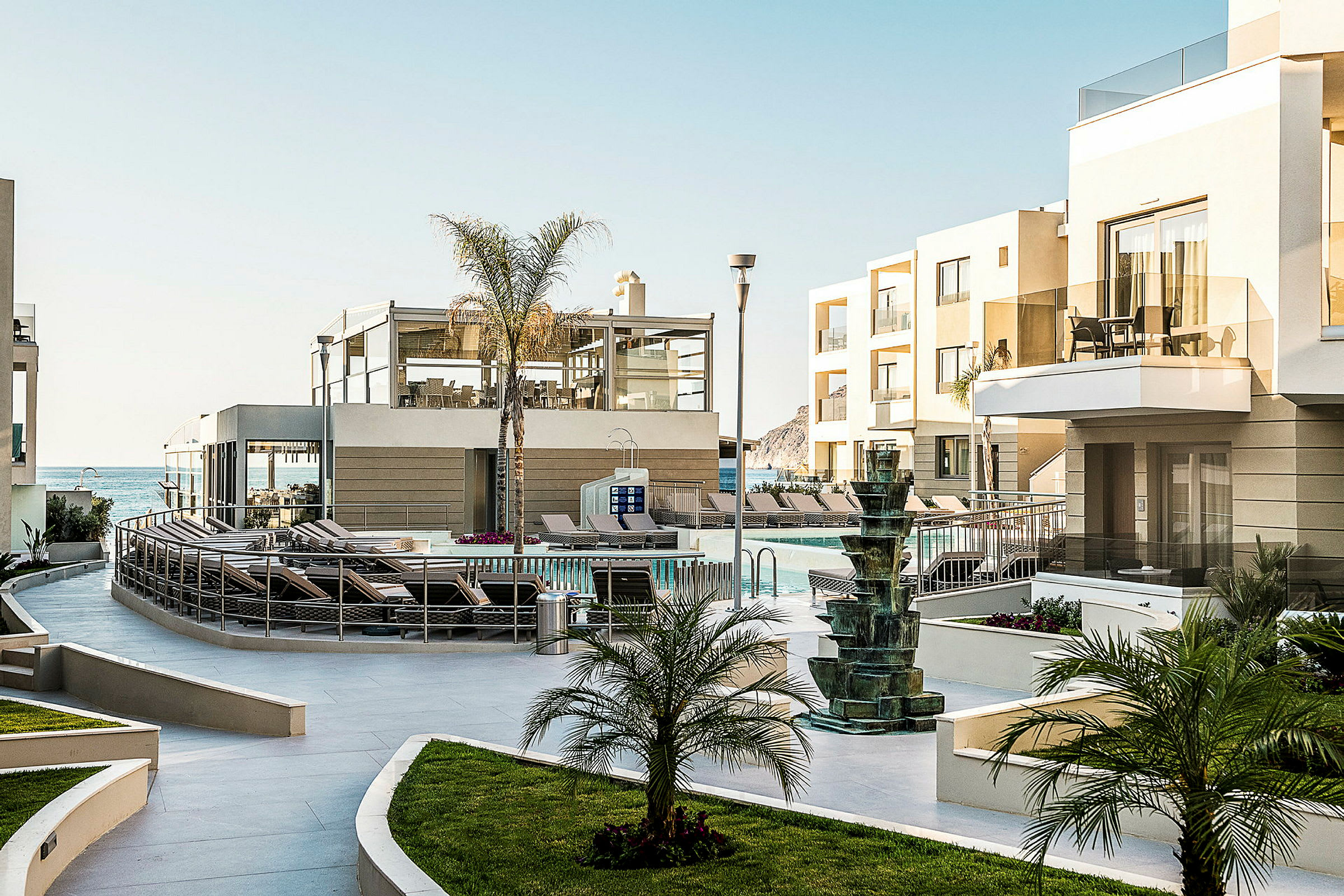 Hotellets utomhusområde med pool, solstolar och grönska. (AI-genererad text)