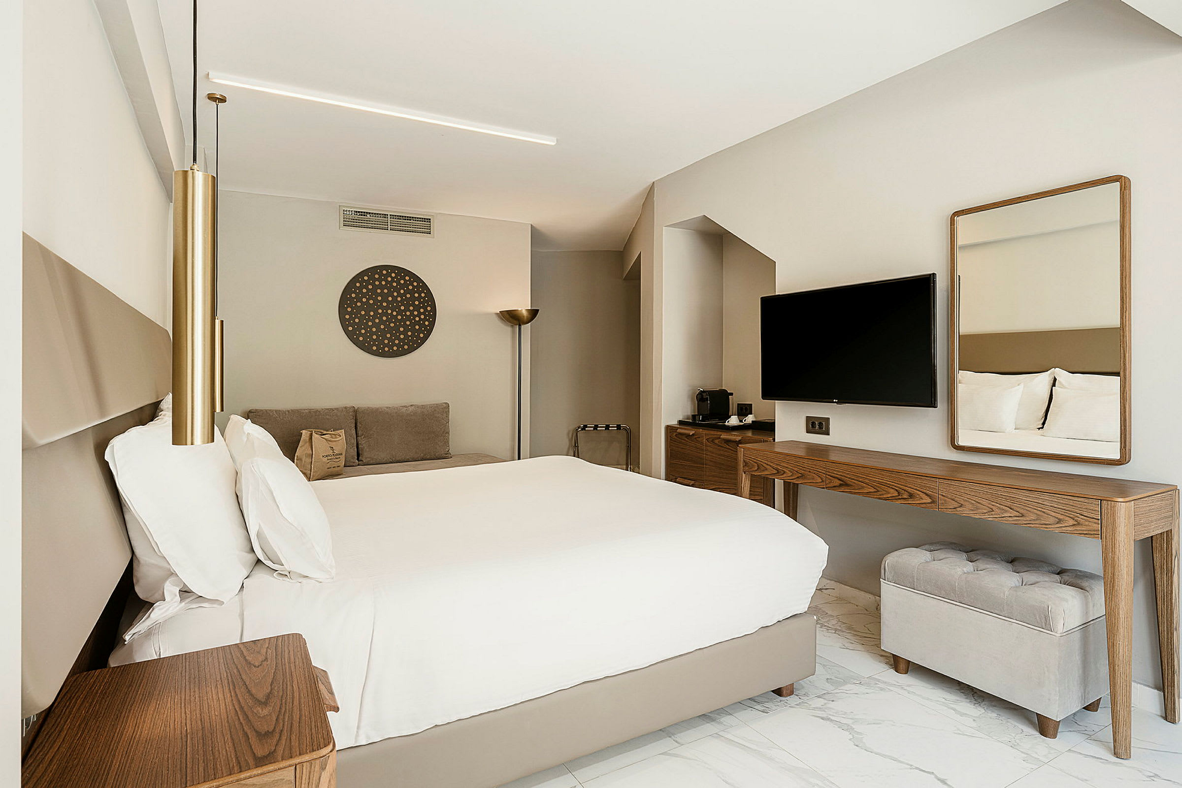 Ett hotellrum med stor säng, noggrant inredda möbler samt en tv på väggen. (AI-genererad text)