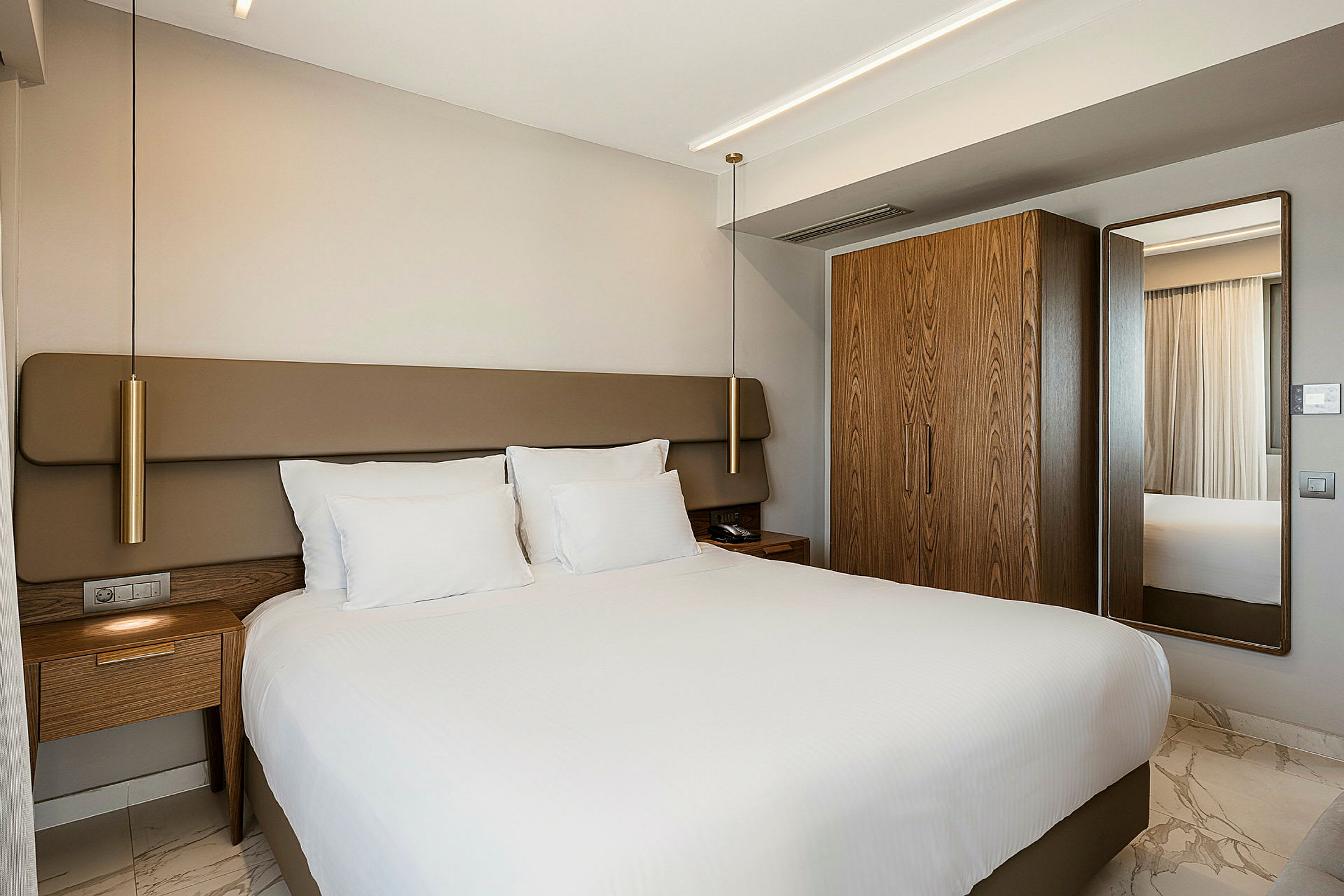 Hotellrum med en stor säng, vita lakan och träinredning. (AI-genererad text)