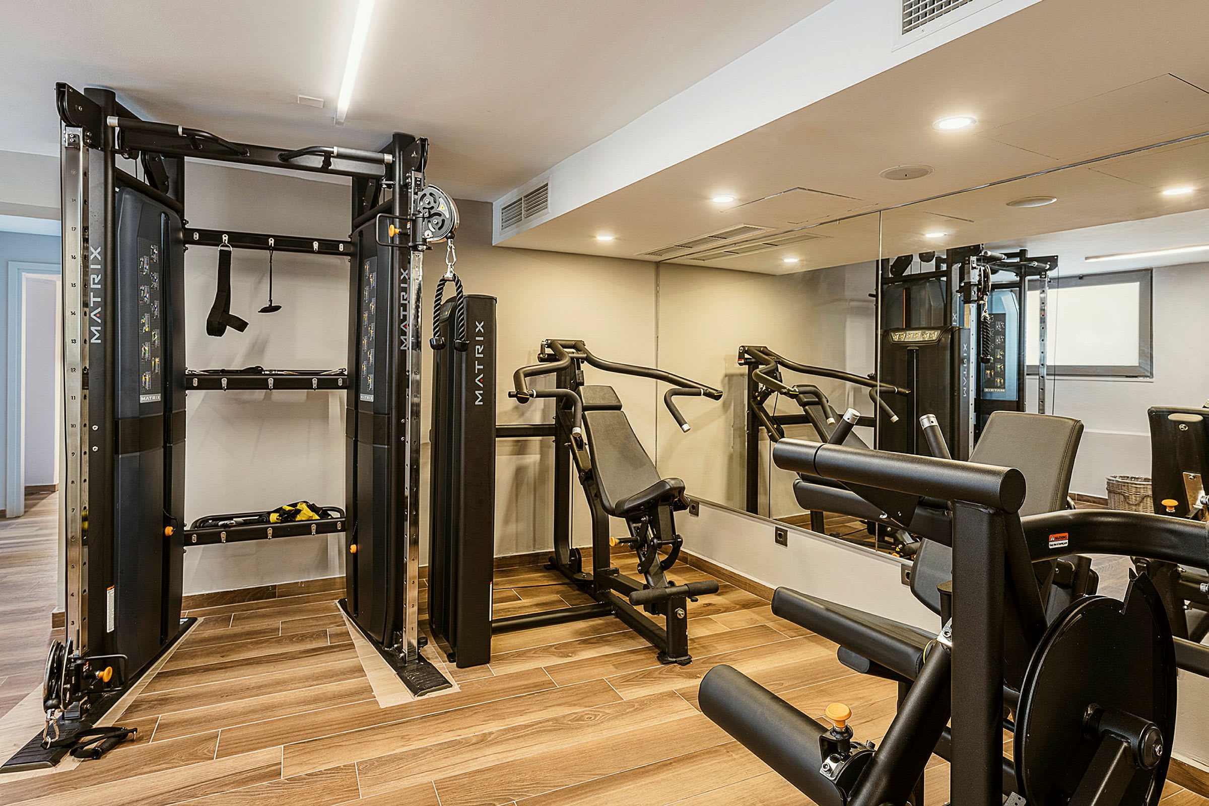Ett gym med träningsutrustning, inklusive en multigym-maskin och en bänkpress. (AI-genererad text)