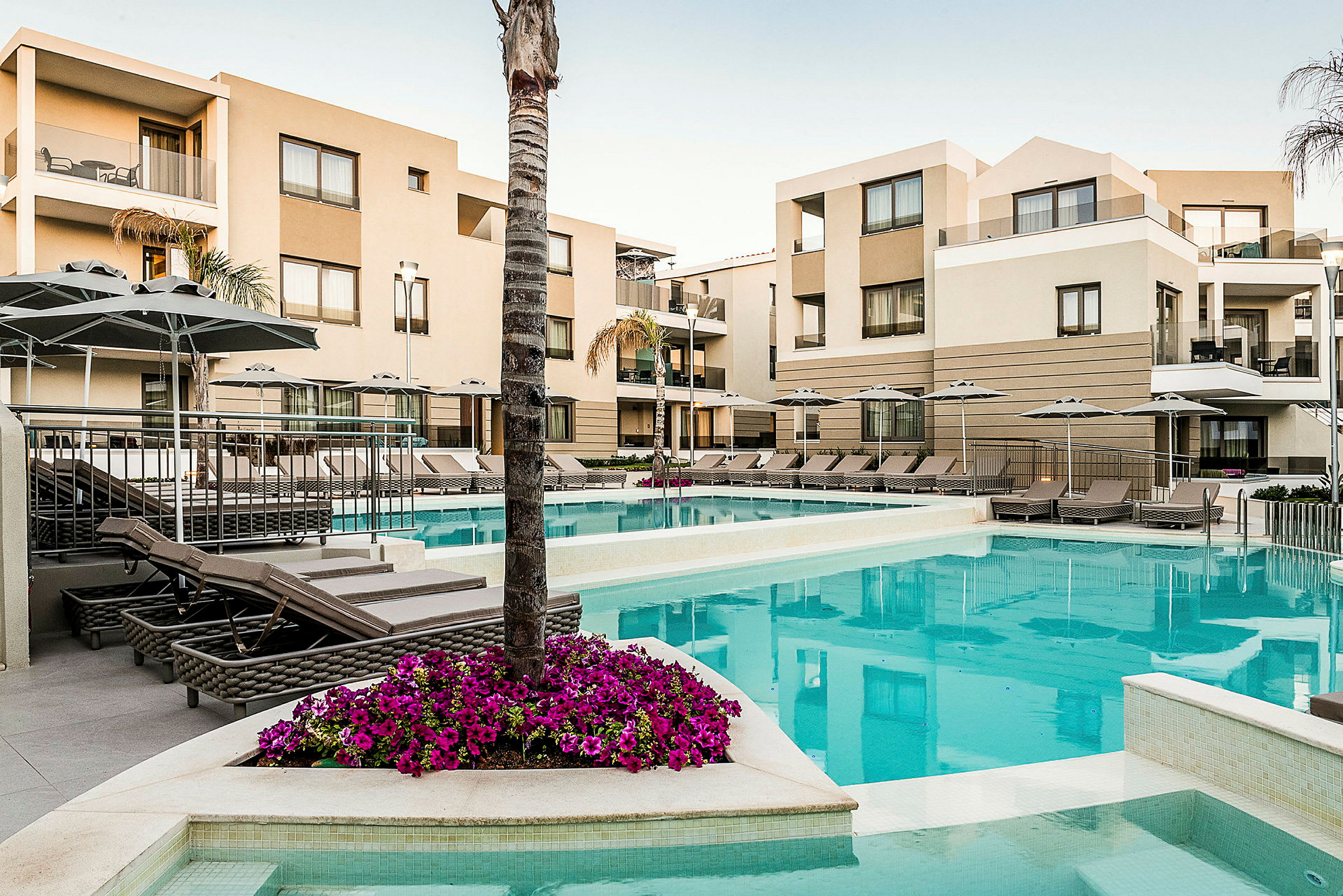 Bild av hotellkomplex med pool och solstolar, omgivna av moderna byggnader. (AI-genererad text)