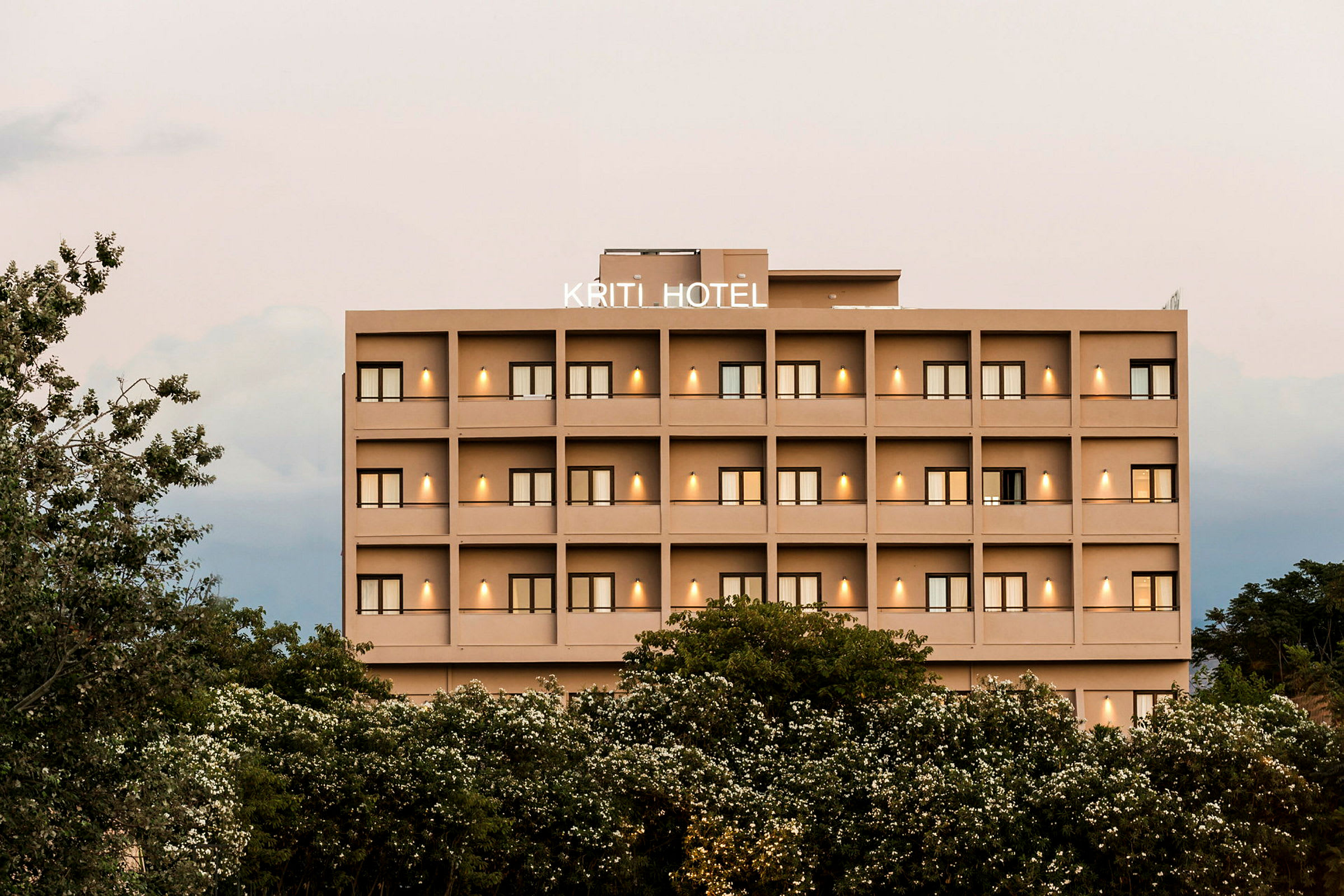 Hotellbyggnad med flera våningar och balkonger, omgiven av grönska. (AI-genererad text)