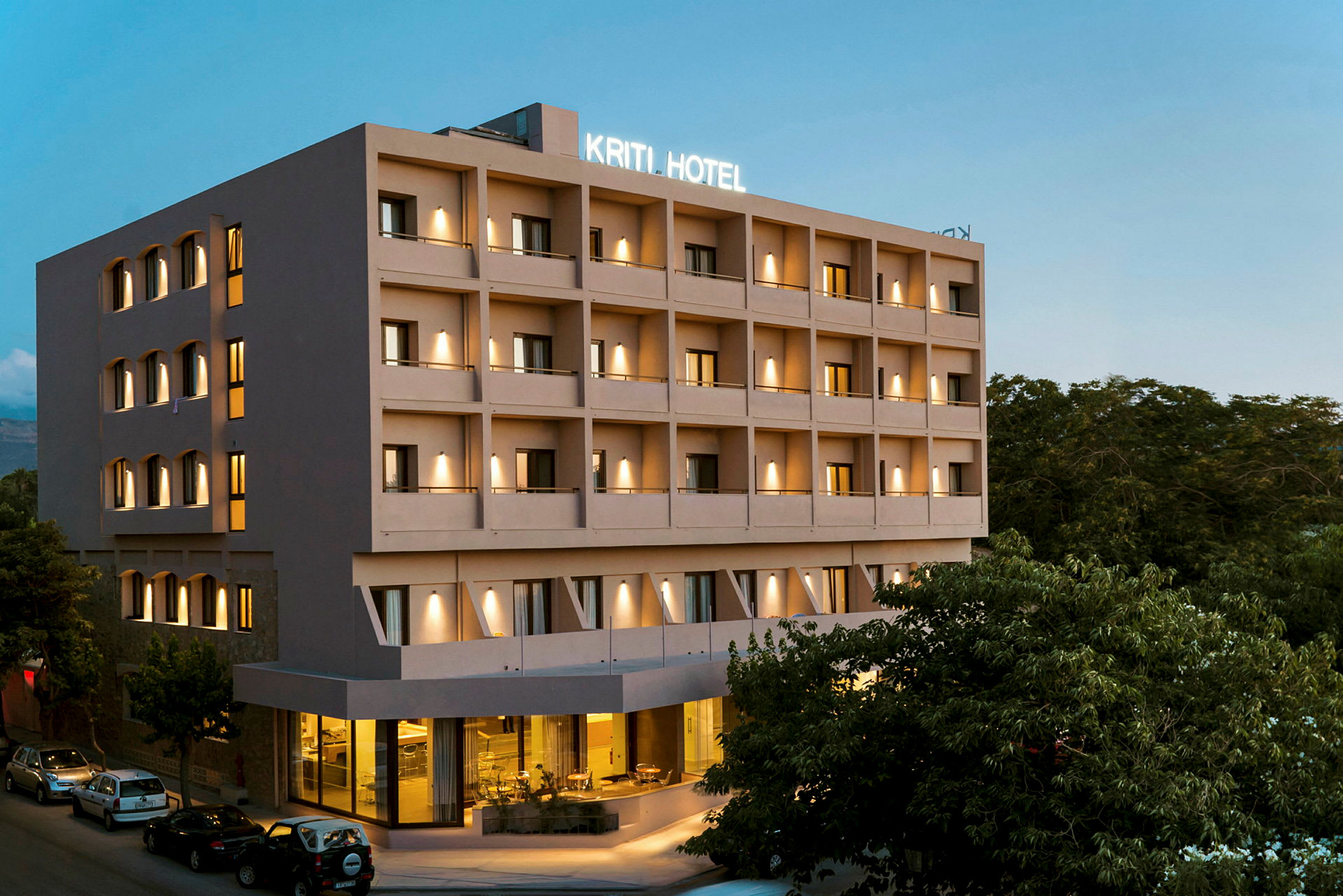Hotellbyggnad med flera våningar, belysning och parkering vid ingången. (AI-genererad text)