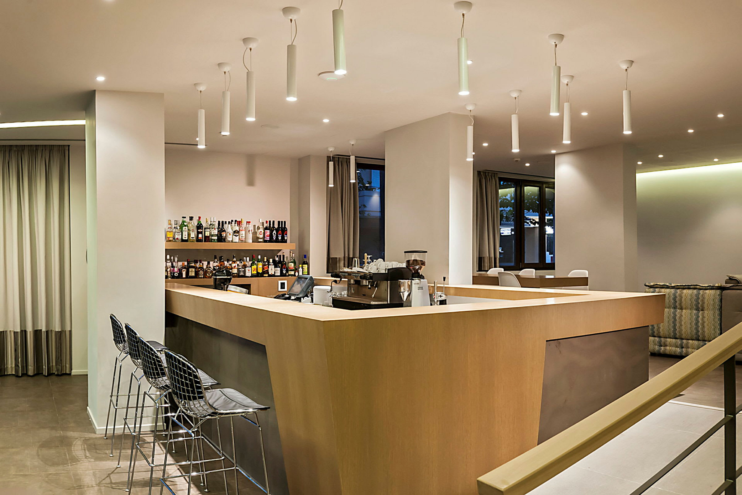 Bild av en modern hotellbar med trädisk, stolar och hyllor med flaskor. (AI-genererad text)