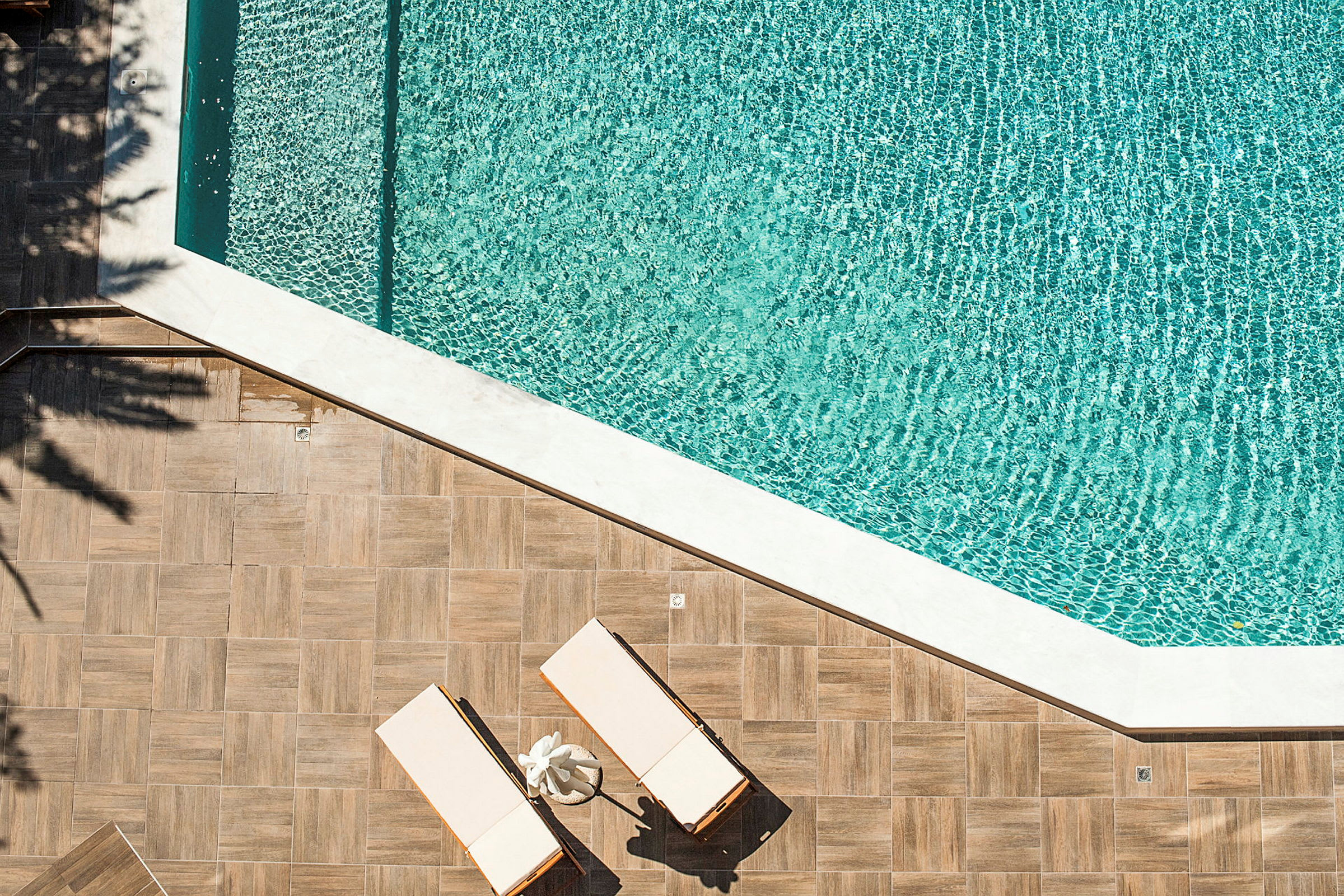 Två solstolar på en trätrall intill en swimmingpool. (AI-genererad text)