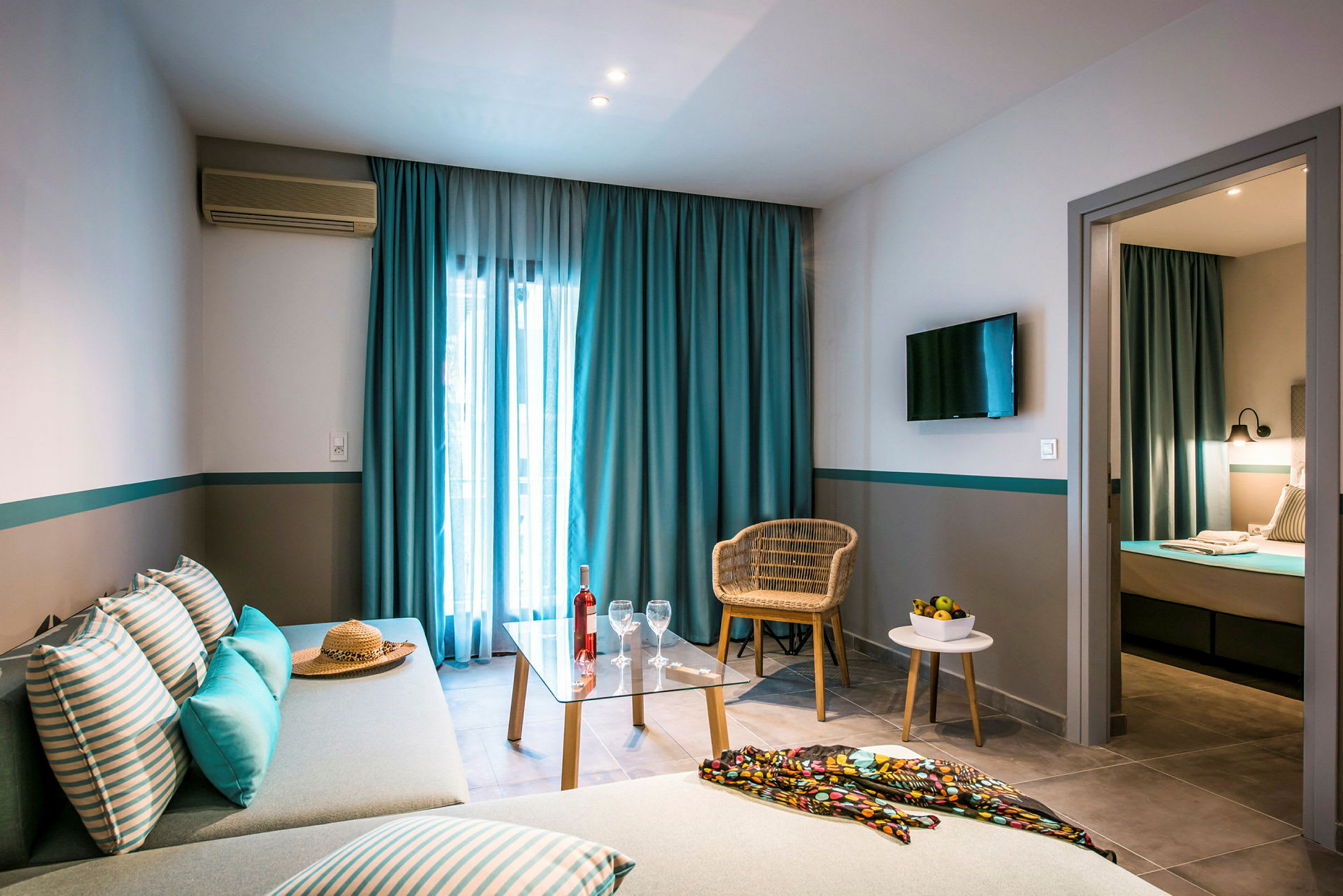 Bild av ett hotellrum med soffa, bord och stol, samt säng i ett separat sovrum. (AI-genererad text)
