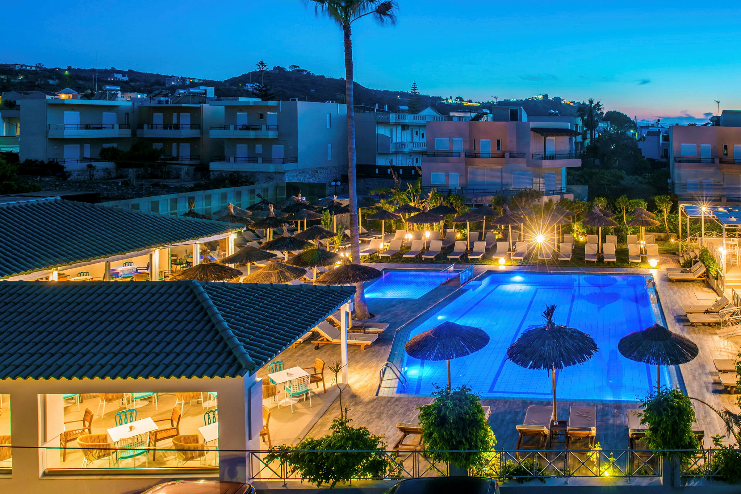 Upplyst hotellområde med pool och solstolar på kvällen. (AI-genererad text)