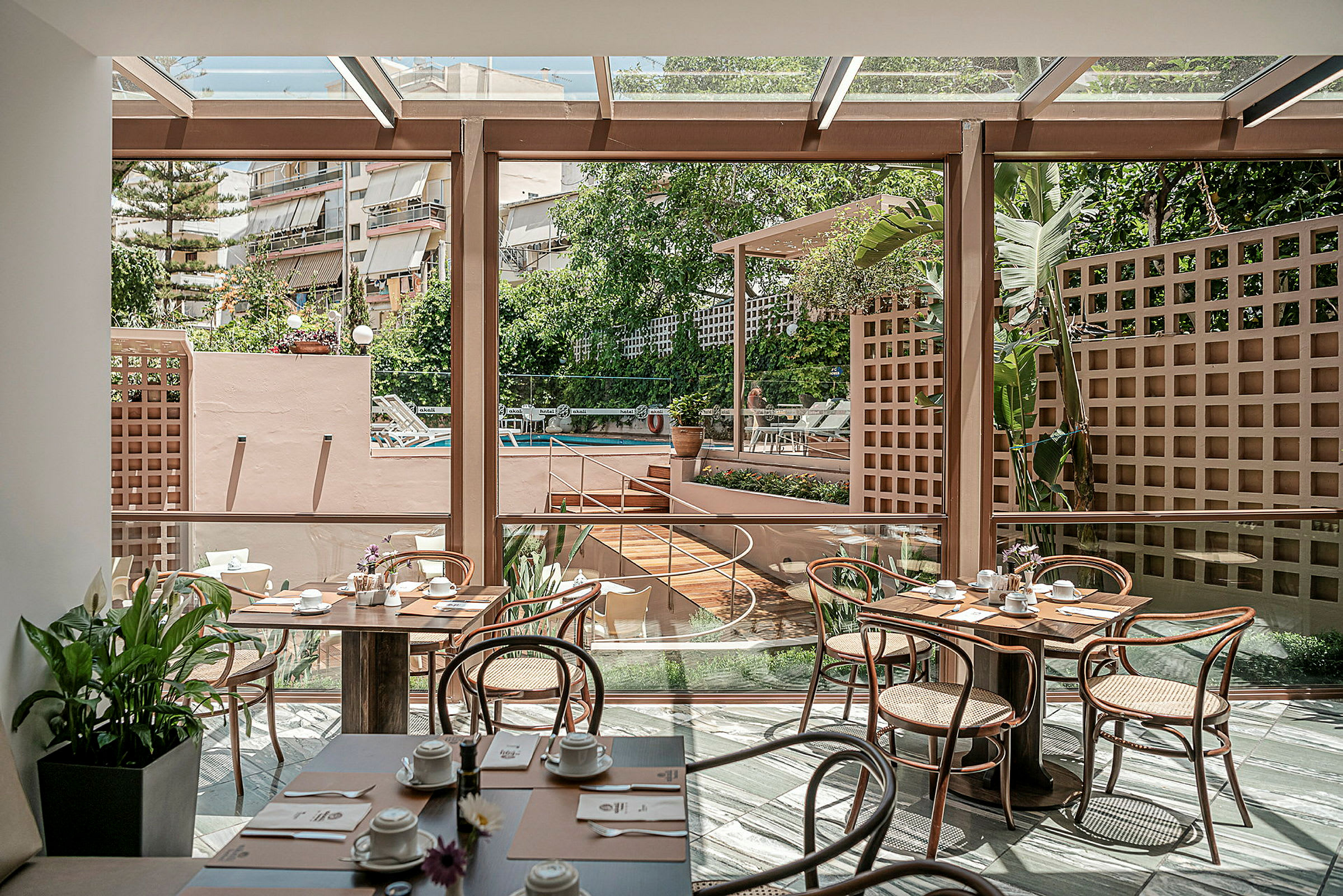 Interiör av en ljus restaurang med glasväggar och utsikt över en utomhuspoolområde. (AI-genererad text)