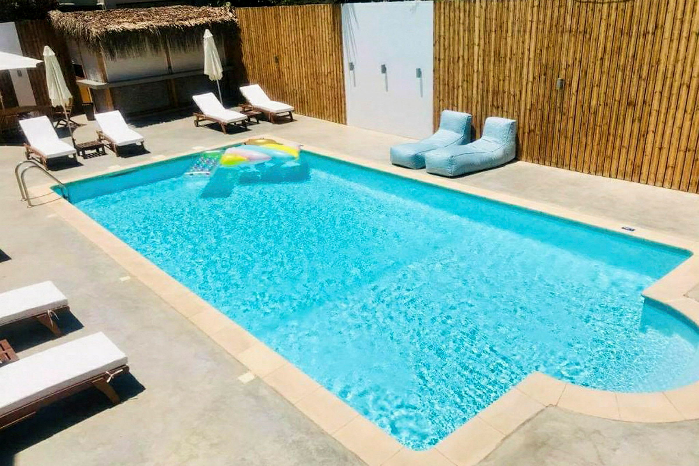 Utomhuspool med solstolar och badleksak. (AI-genererad text)
