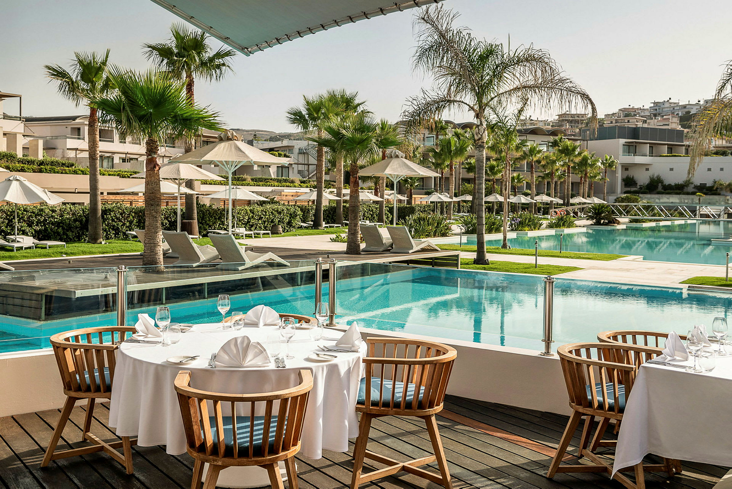 Ett uppdukat bord vid en pool på ett hotellområde. (AI-genererad text)