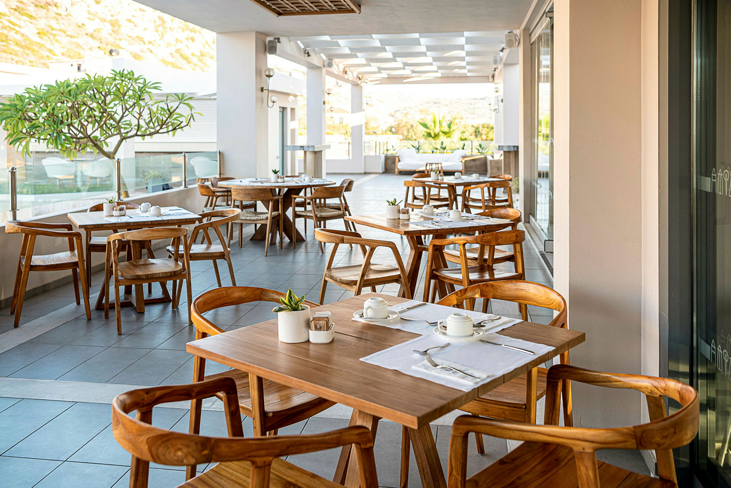 En utomhusrestaurang med dukade bord och trästolar. (AI-genererad text)