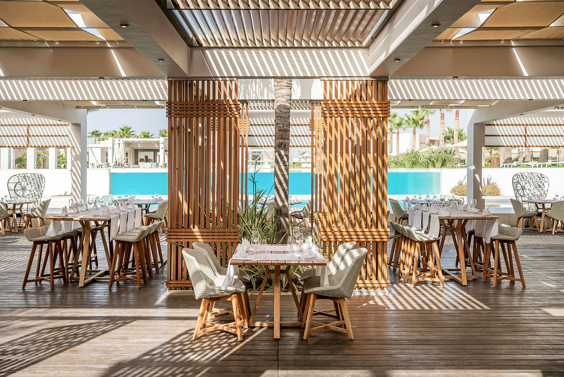 Restaurang med trämöbler och utsikt över en pool. (AI-genererad text)
