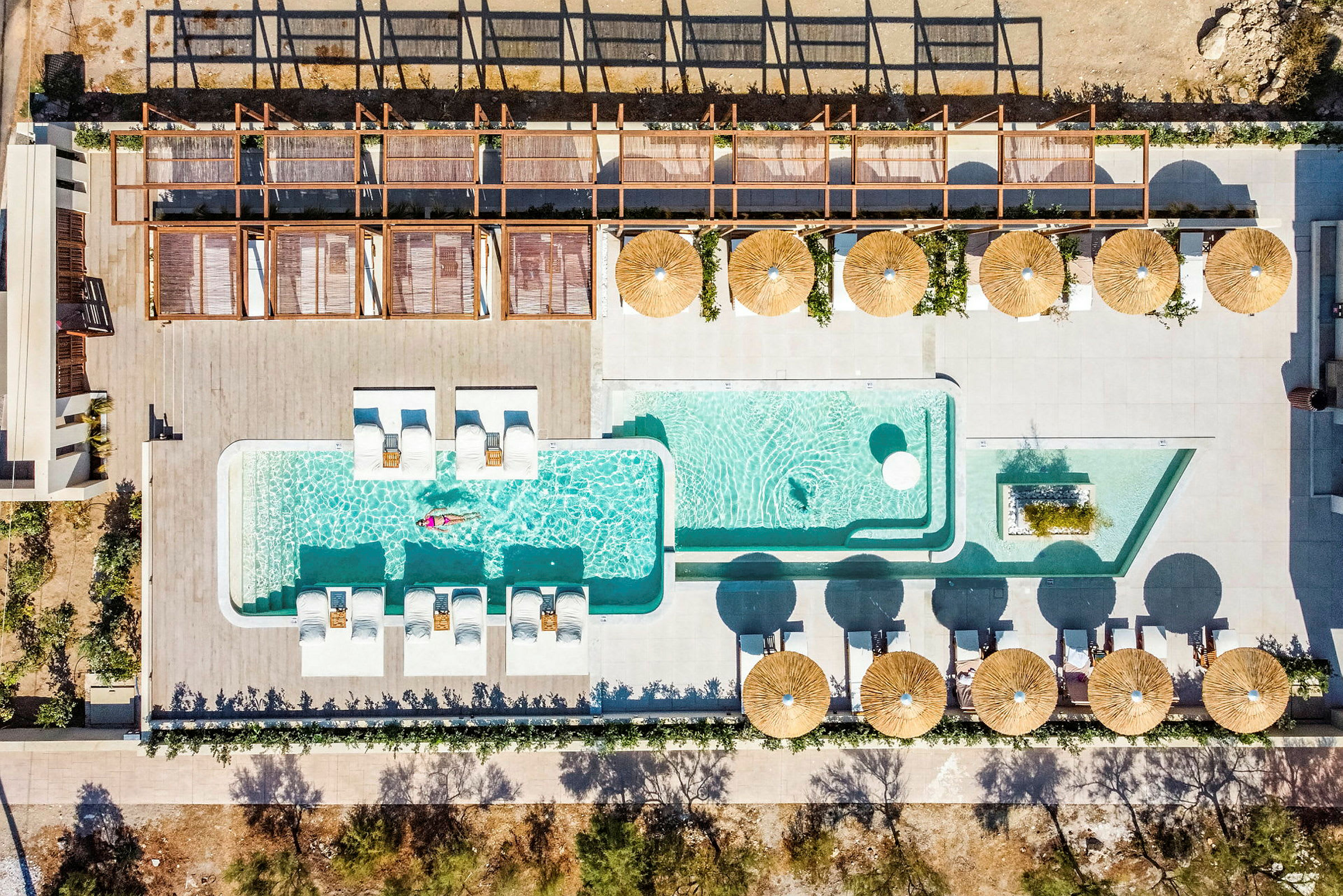 Bild av en pool med solstolar och parasoller sedd uppifrån. (AI-genererad text)