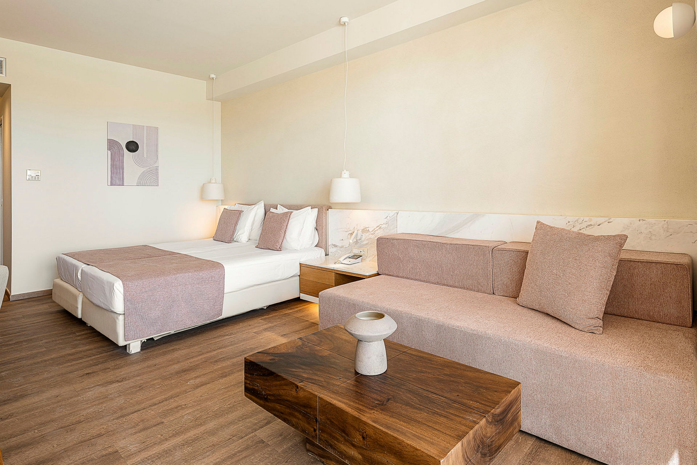 Ett hotellrum med en säng, en soffa och ett träbord. (AI-genererad text)