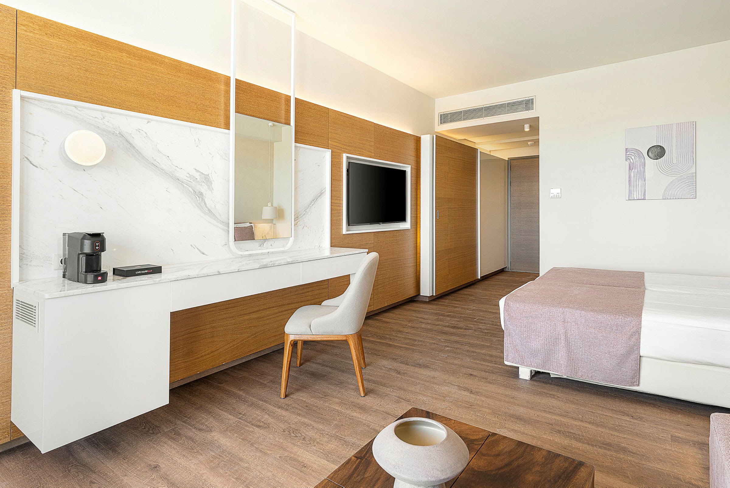 Modernt hotellrum med skrivbord och spegel, säng och TV. (AI-genererad text)