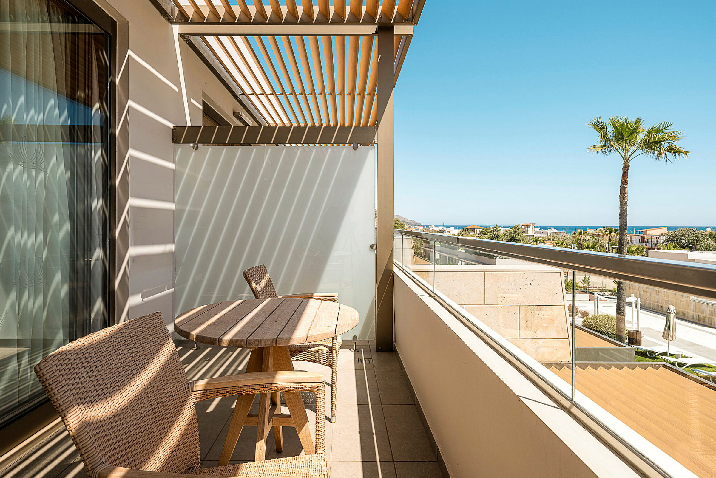 En terrass med trämöbler och pergola, med havsutsikt i bakgrunden. (AI-genererad text)