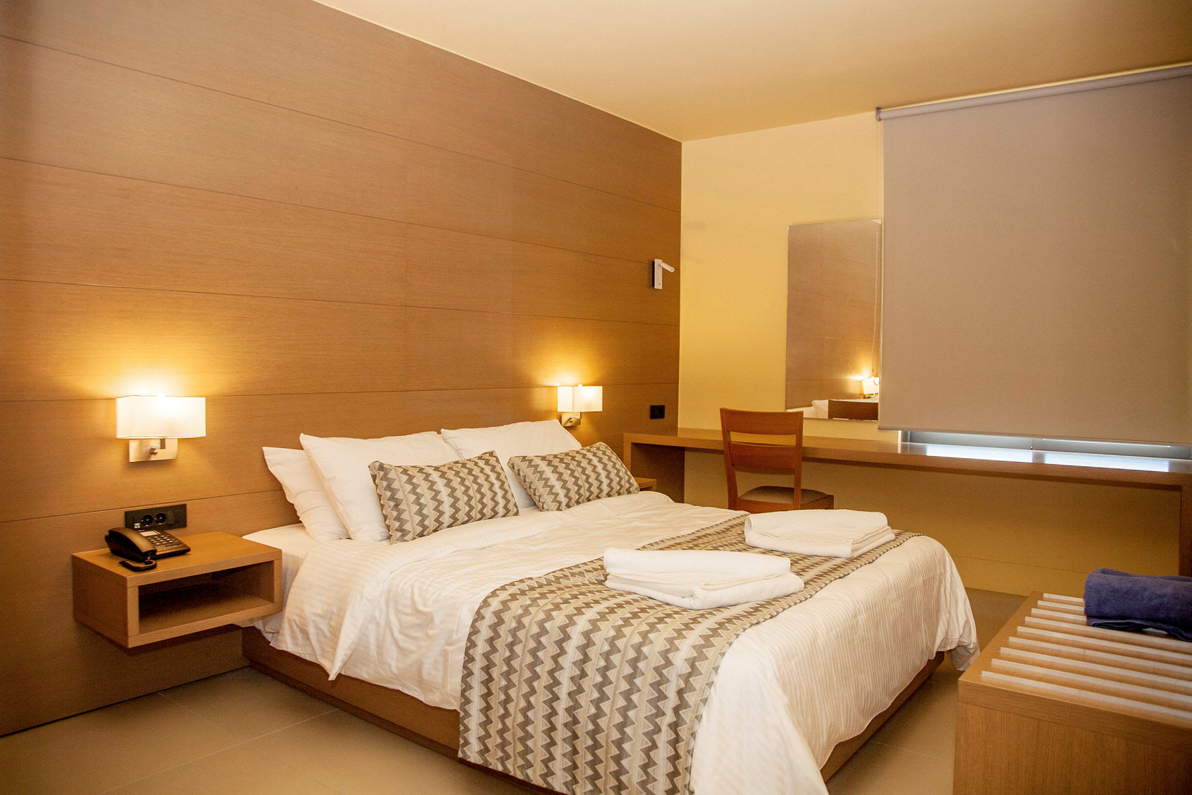 Ett hotellrum med en dubbelsäng, träinredning och ett skrivbord. (AI-genererad text)