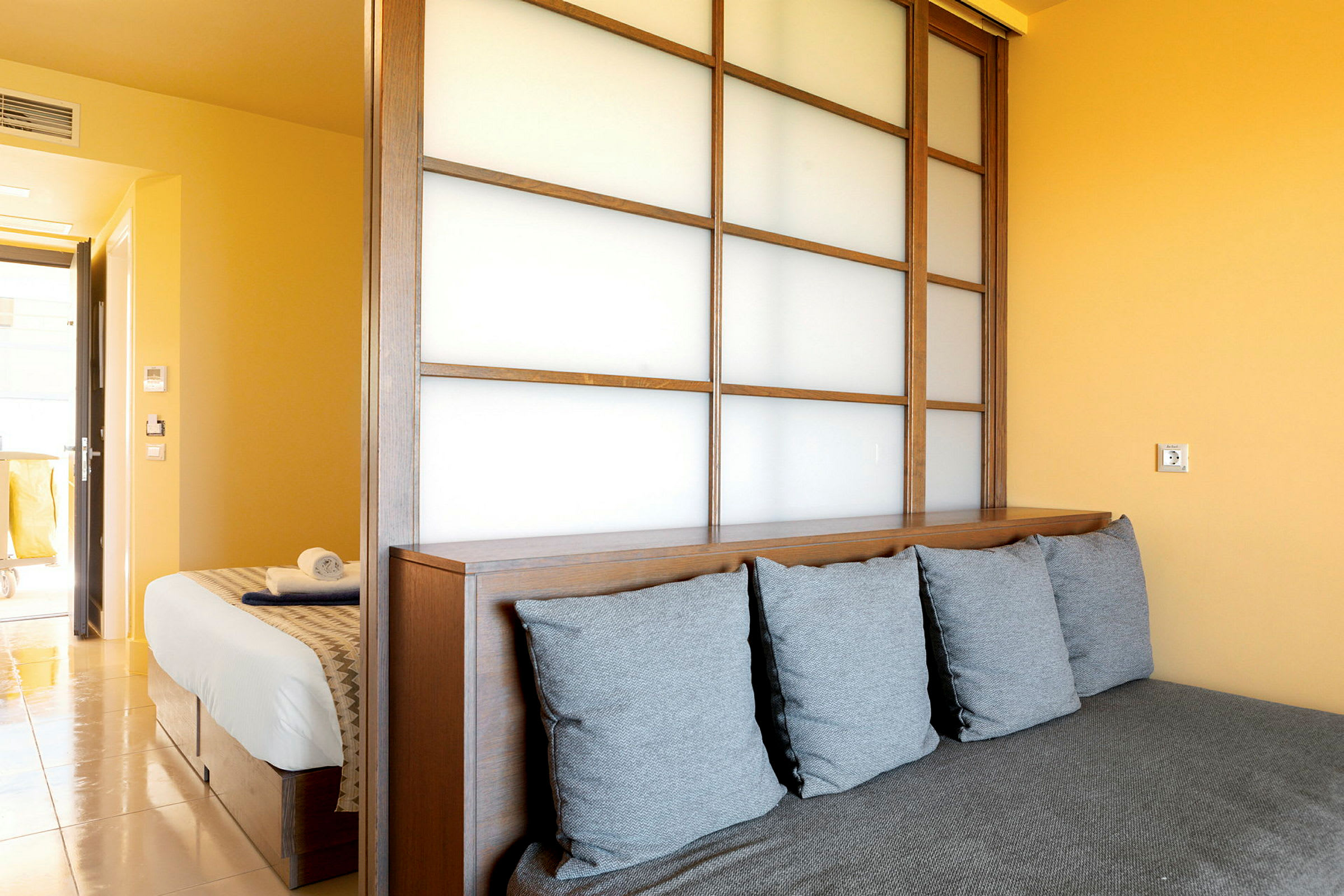 En hotellrum med en delande träpanel, en säng och en soffa. (AI-genererad text)