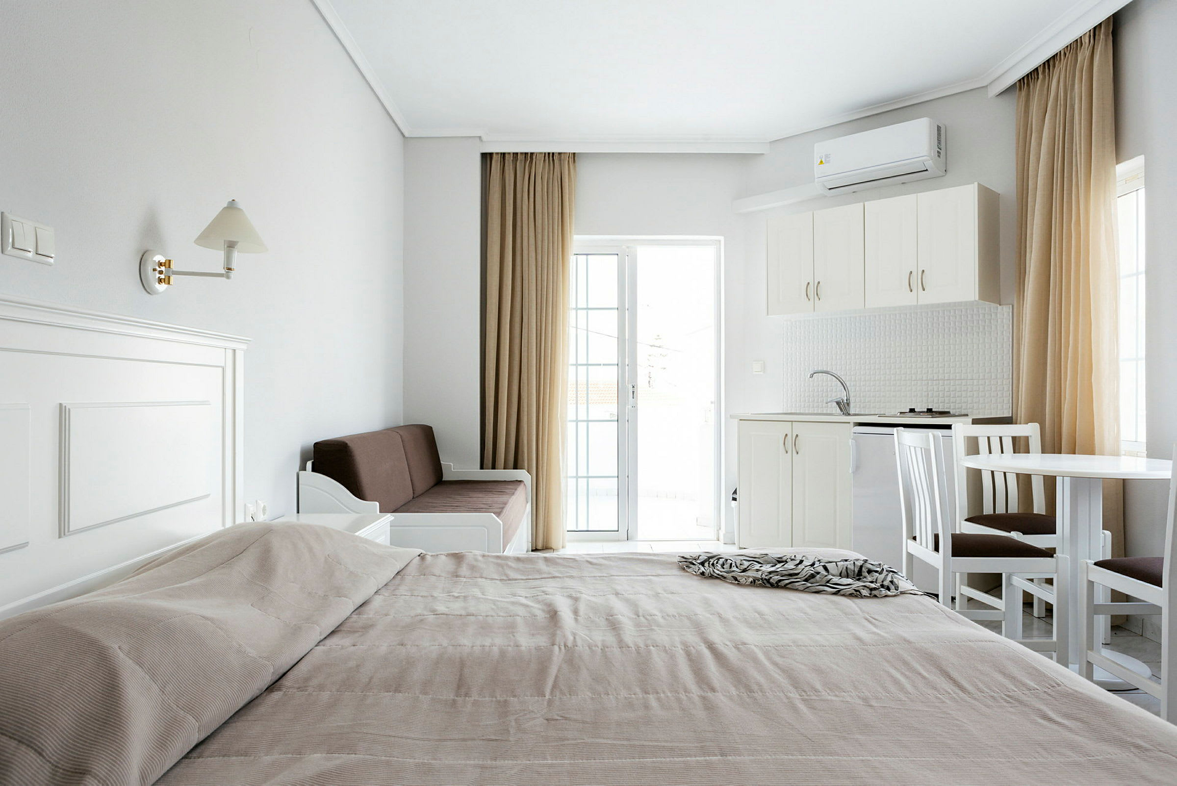 En översikt av ett hotellrum med en säng, soffa, kök och matbord. (AI-genererad text)