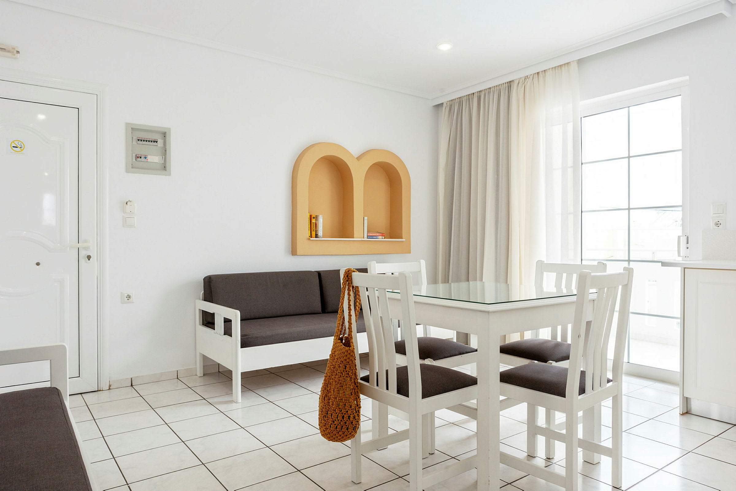 En ljus inomhusmiljö med vita möbler, ett grått soffset och beige detaljer på väggen. (AI-genererad text)