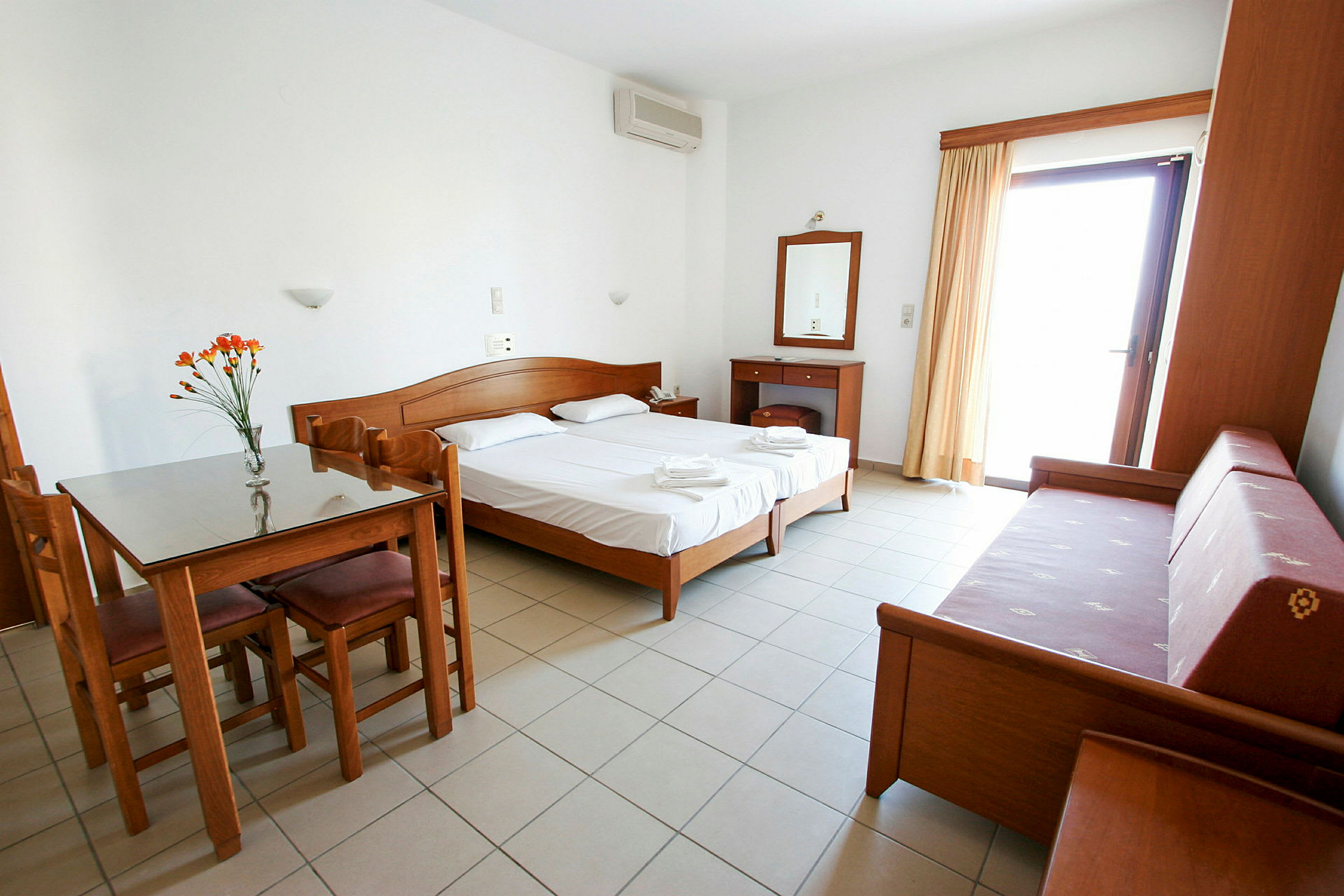 Bild på ett hotellrum med två enkelsängar, ett bord med stolar, en soffa och ett skrivbord. (AI-genererad text)