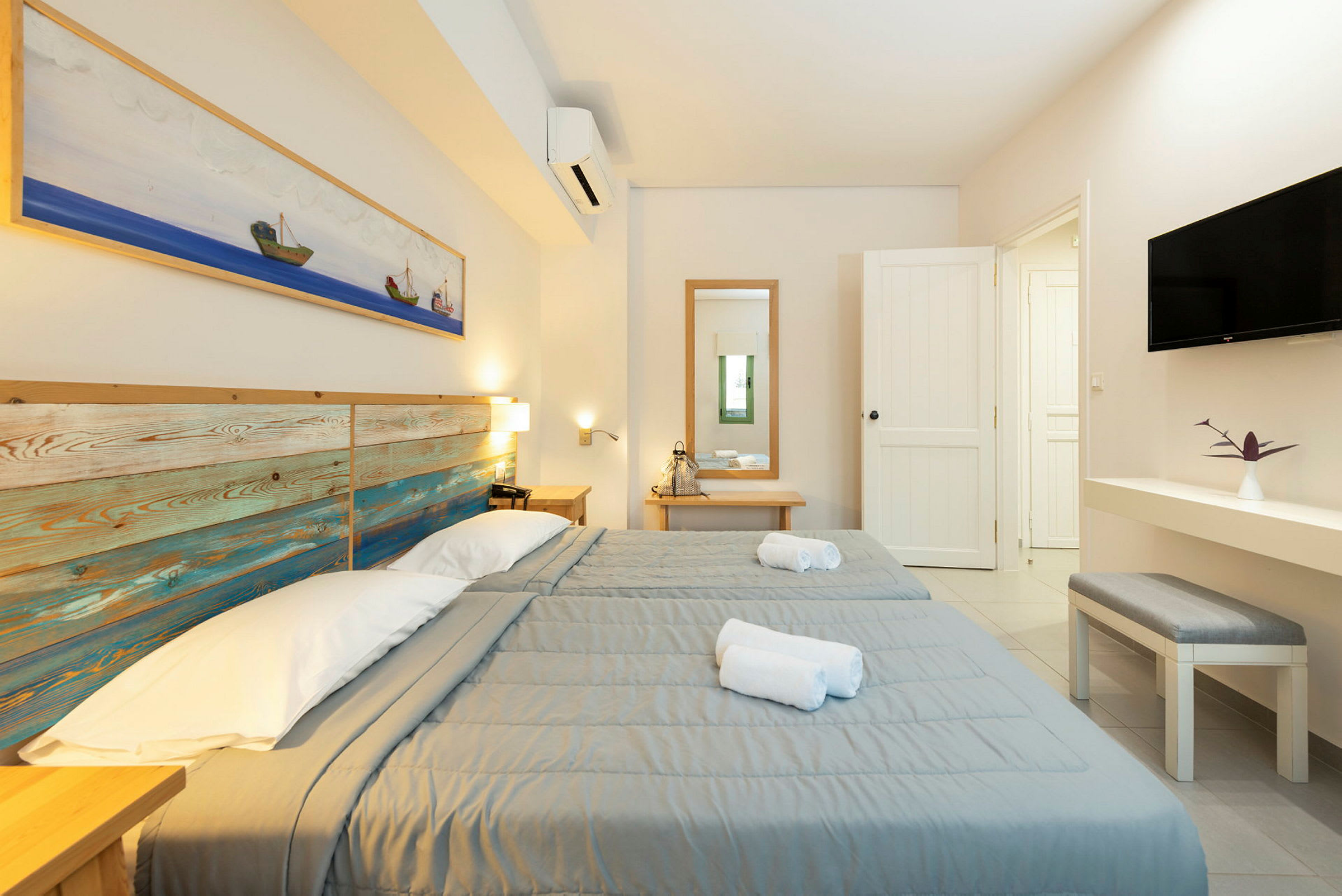 Två enkelsängar med gråa överkast i ett ljust hotellrum. (AI-genererad text)