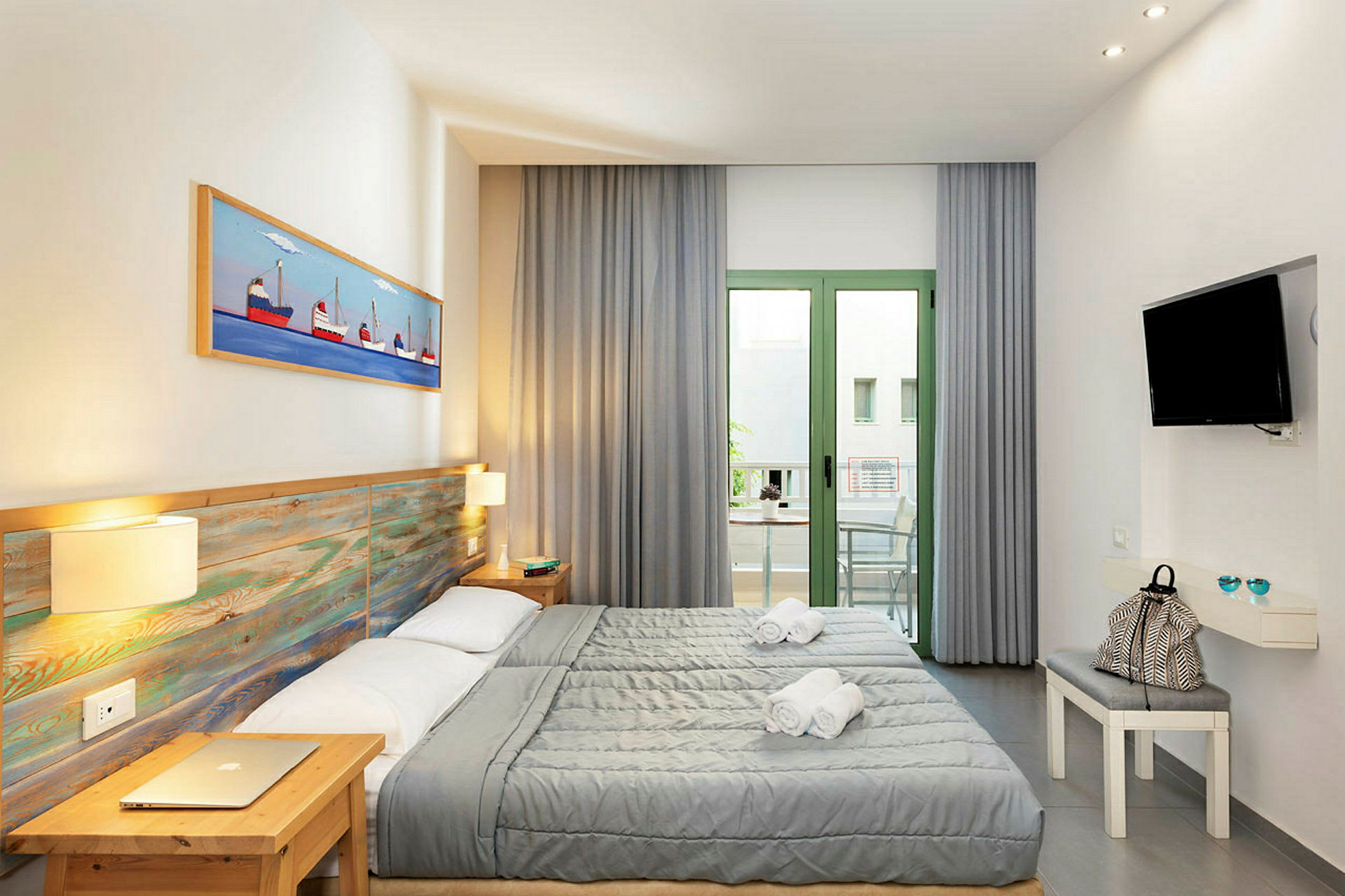 Ett hotellrum med två enkelsängar, en möblerad balkong och en väggmonterad TV. (AI-genererad text)