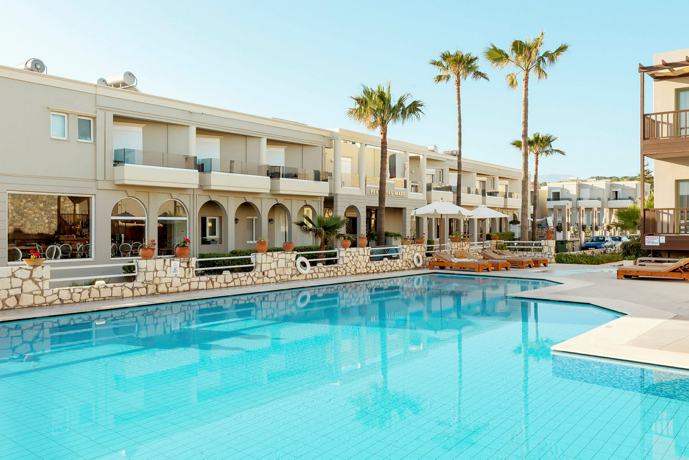 Modern byggnad med solstolar och pool framför. (AI-genererad text)