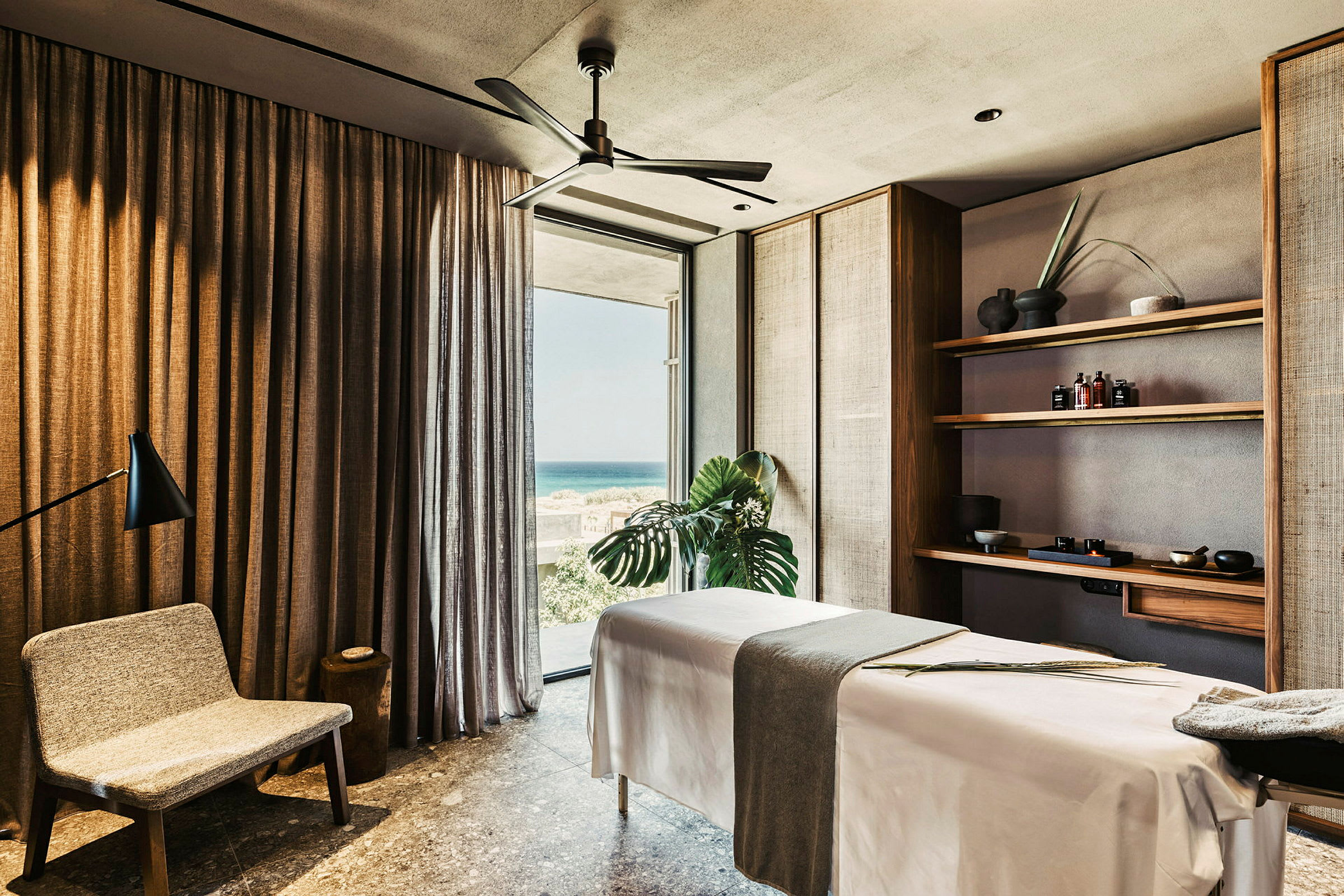 Spa-rum med massagebänk, stol och hyllor med produkter. (AI-genererad text)