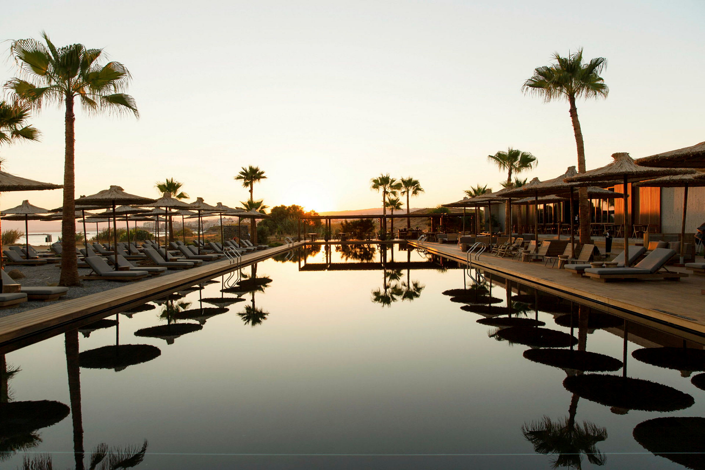 En infinitypool med solstolar och parasoll i en solnedgång. (AI-genererad text)