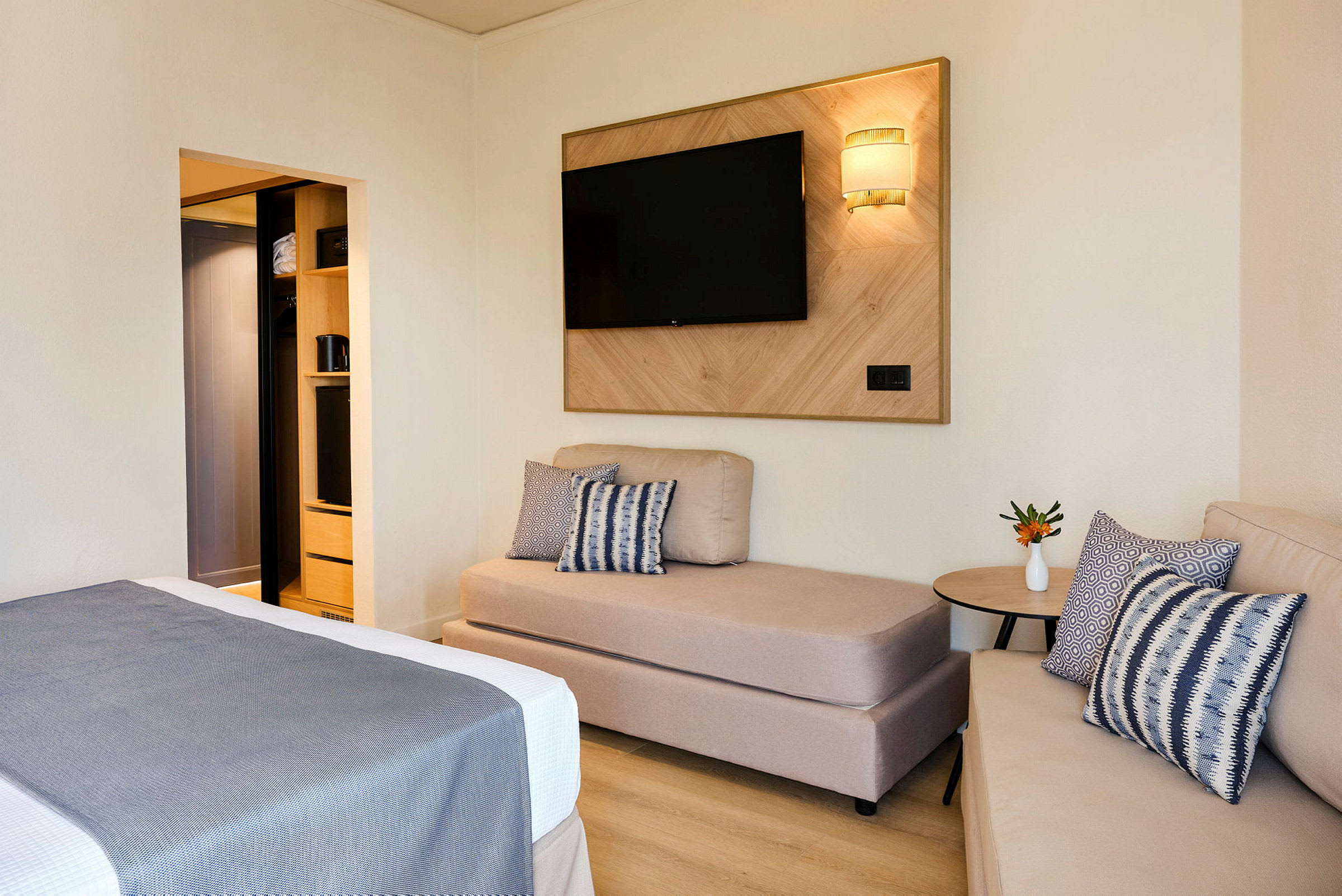 Ett hotellrum med soffa, säng och TV på väggen. (AI-genererad text)